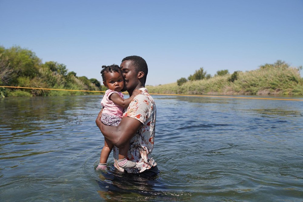  A Haitian man carries his child across the Rio Grand, from Del Rio, TX back to Acuńa, MX. September 2021. 