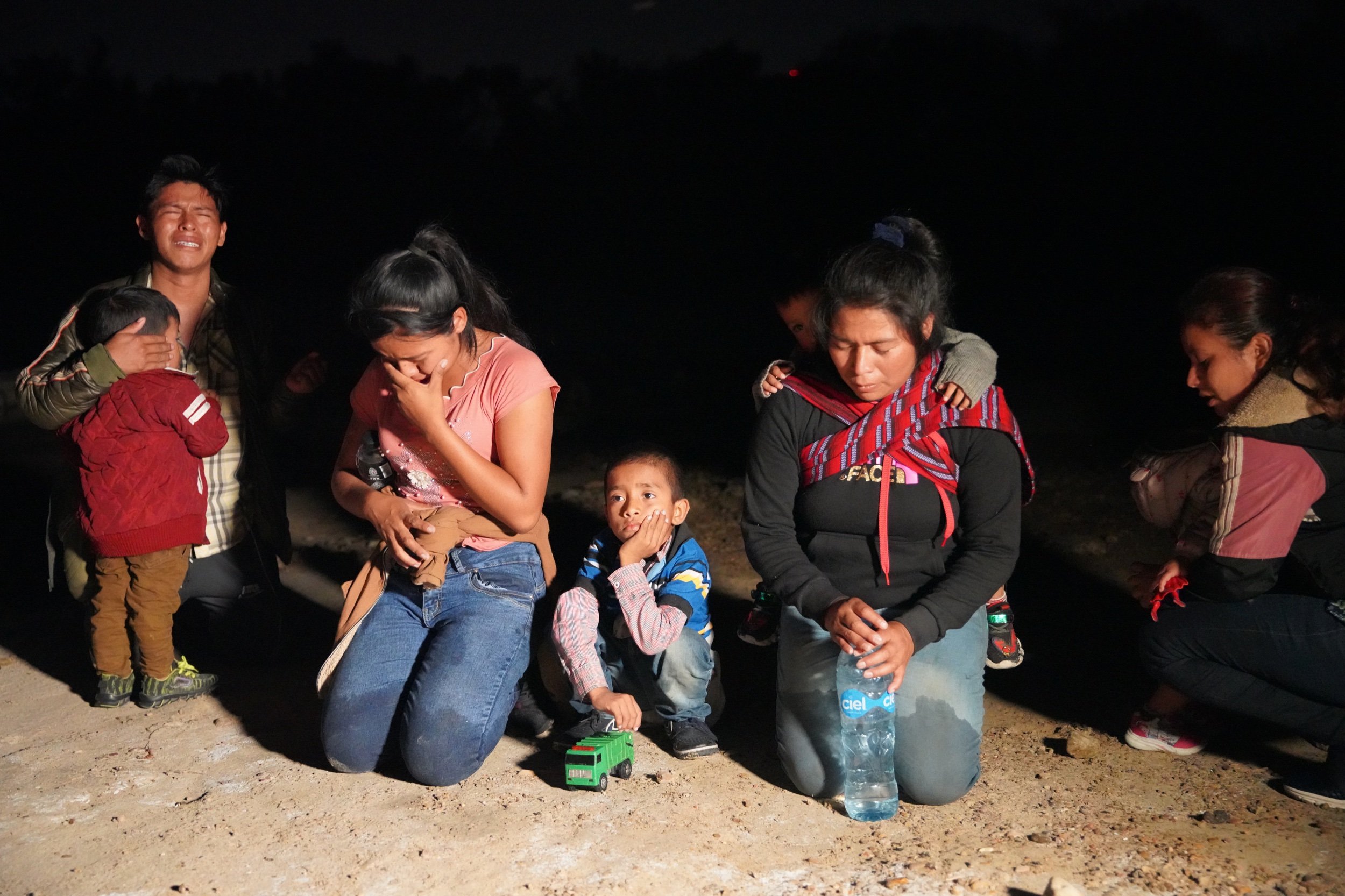  Migrants pray after crossing the Rio Grande river from Mexico into Roma, Texas. July 2021. 