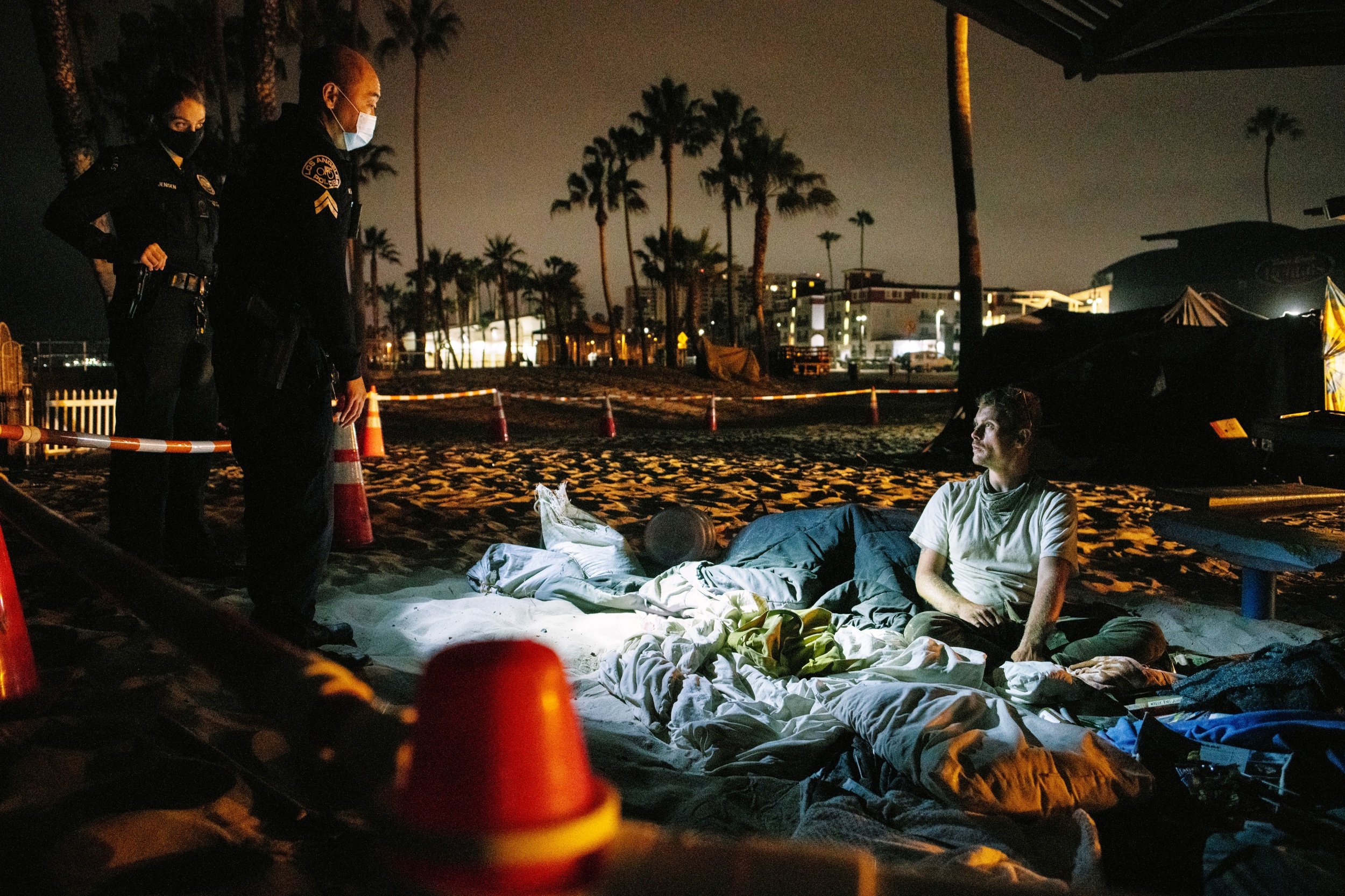  Los Angeles Police surround an unhoused man, sleeping on Venice Beach. In the summer of 2021 the city of Los Angeles carried out massive sweeps of the homeless. July 2021. Venice Beach, Los Angeles, CA.   