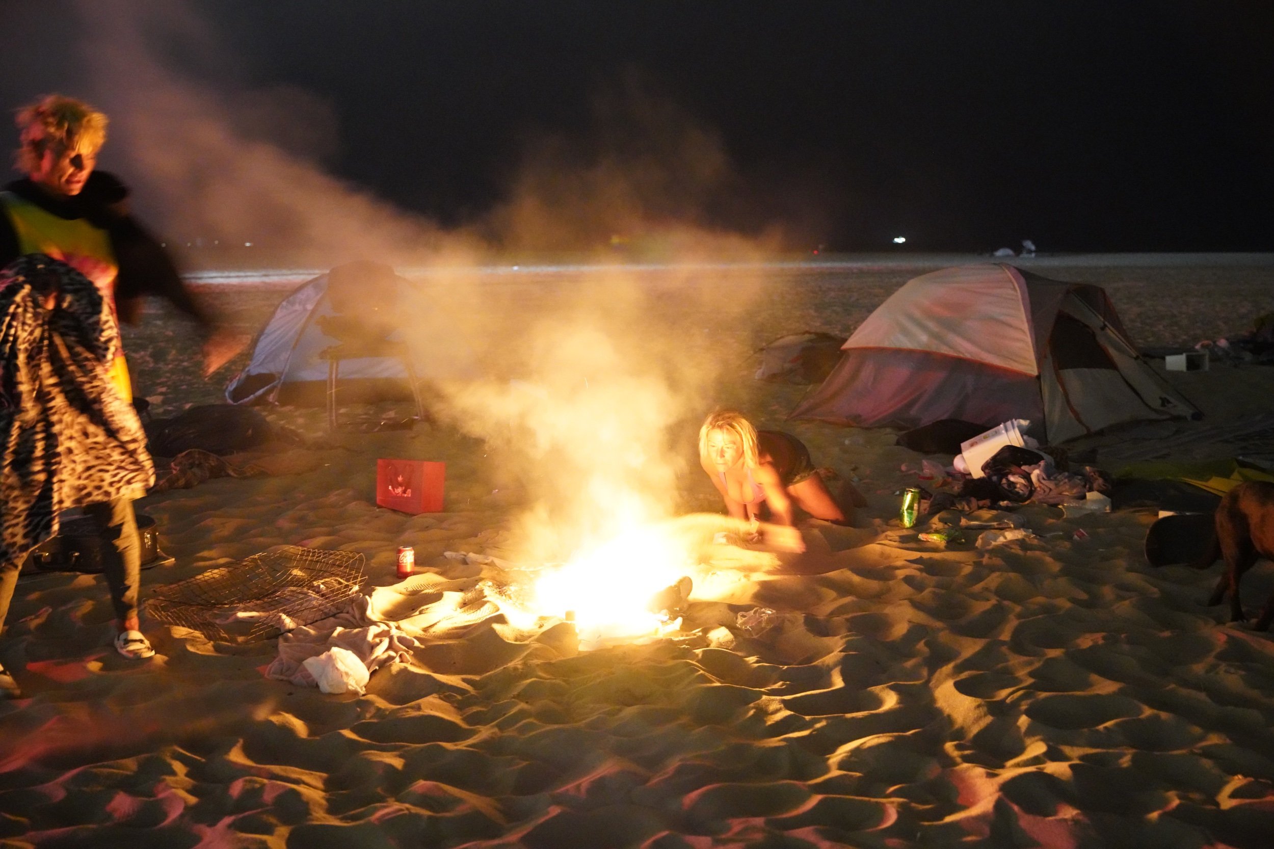  Unhoused residents of the beach quickly work to put out an illegal fire, as police and fire vehicles approach. During the summer of 2021, the city of Los Angeles was sweeping the unhoused off of Venice Beach. Los Angeles, CA. August 2021.  