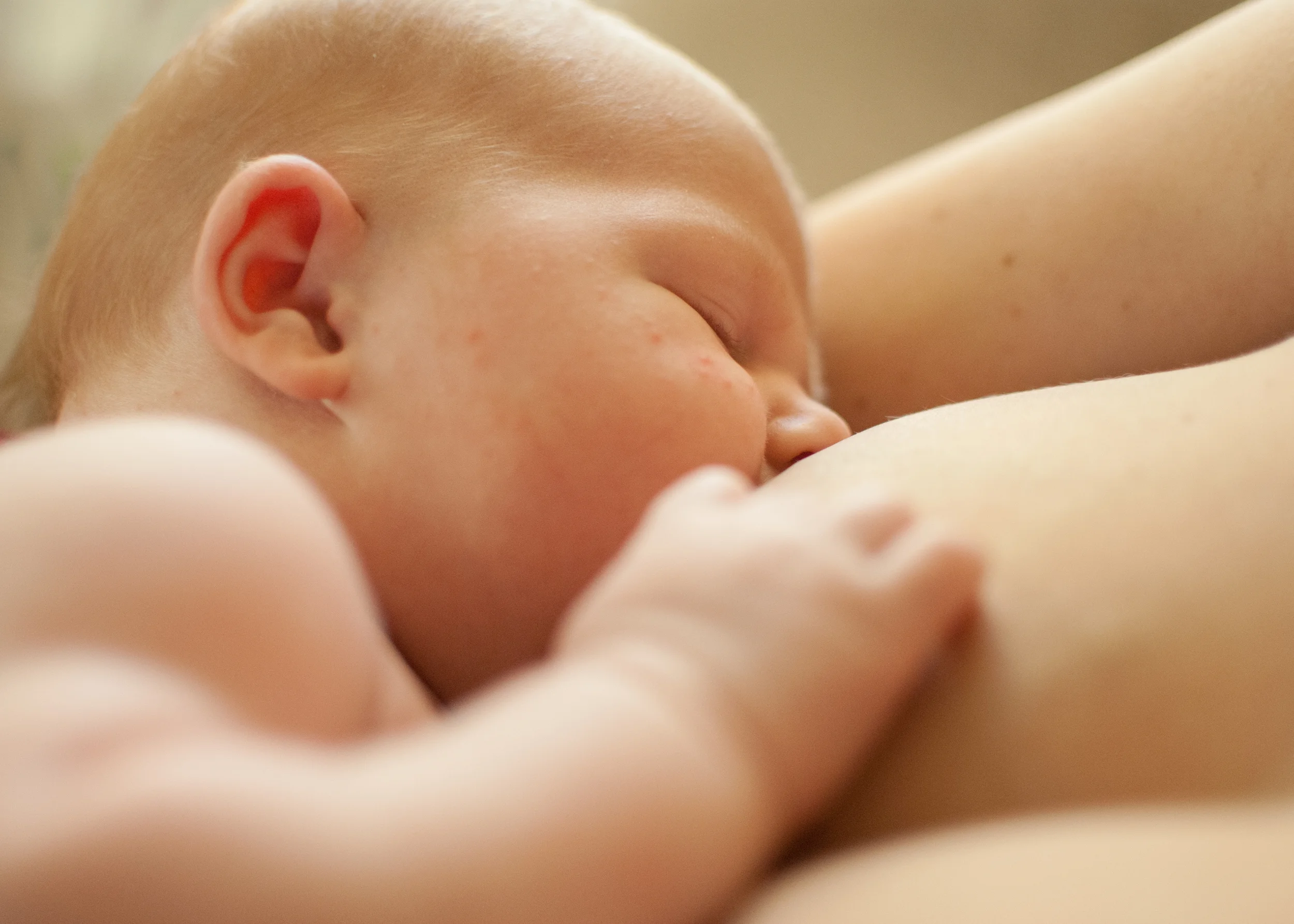 Newborn Teddy feeds in the arms of mother Emily