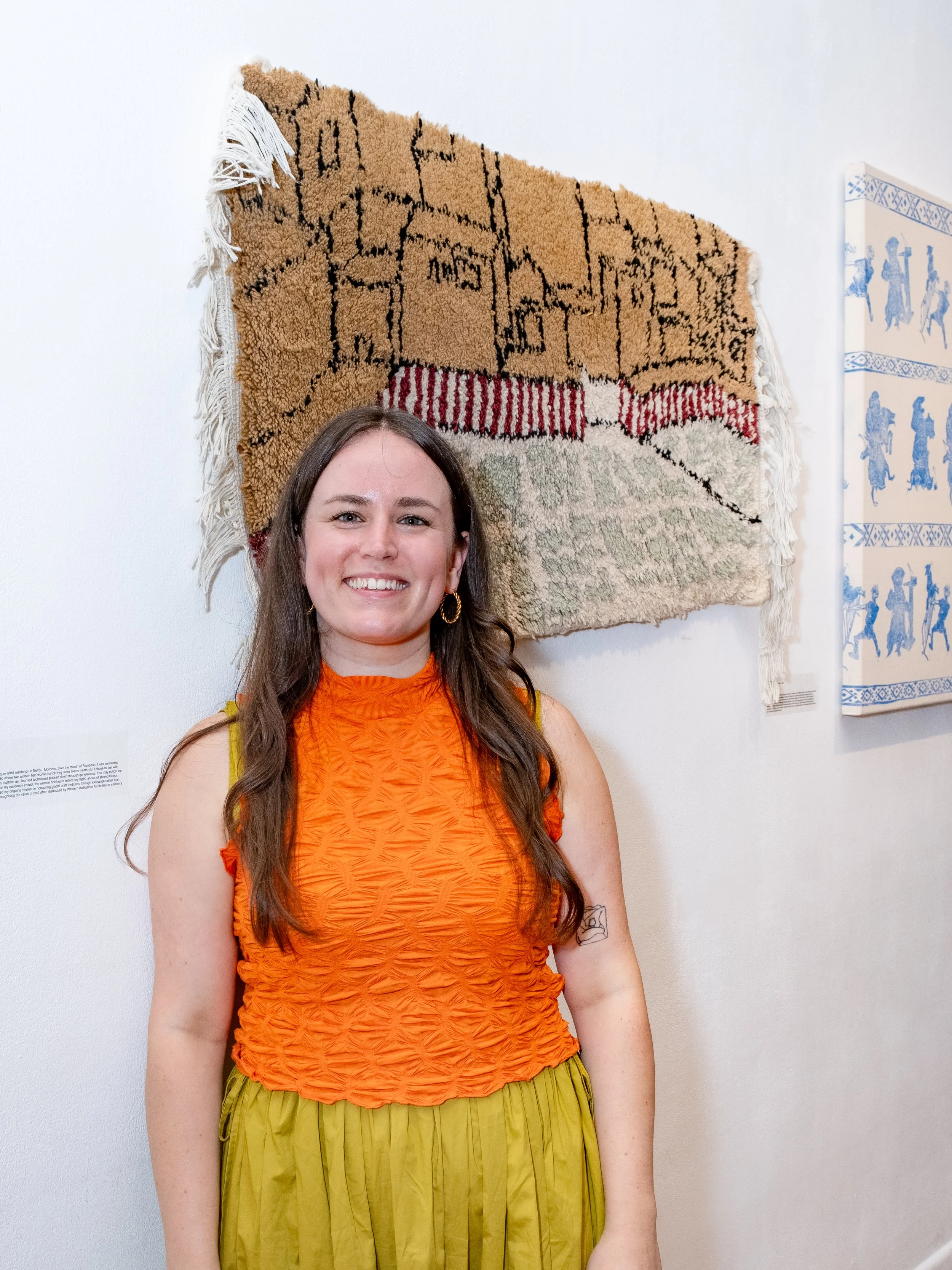 eliza groth artist  standing in front of her hand knotted rug at at october gallery in london 2025 educators exhibition