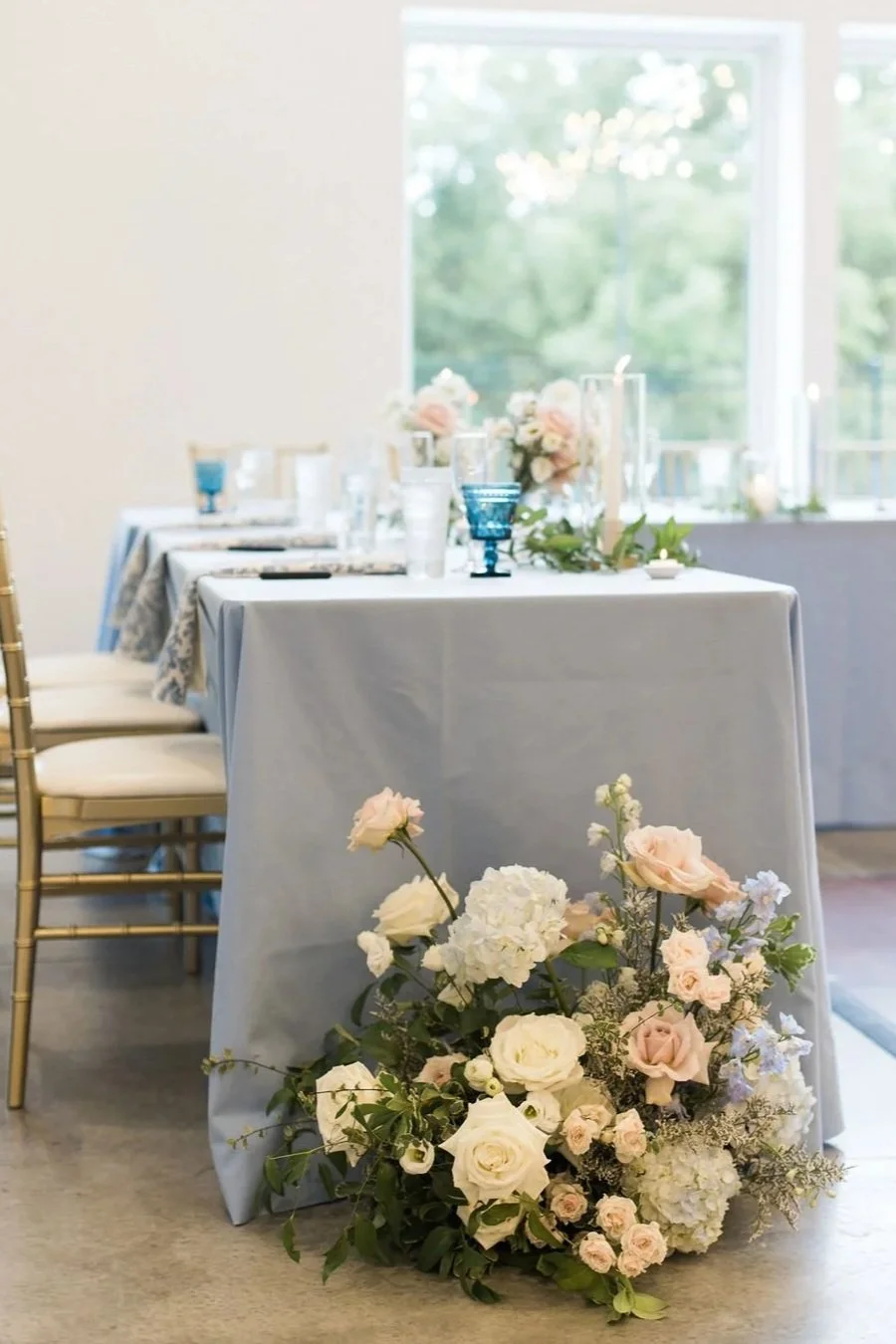 Sweetheart table with a lush white and blush floral ground arrangement designed by 1209 Creative for a Wisconsin wedding, featuring romantic garden style florals