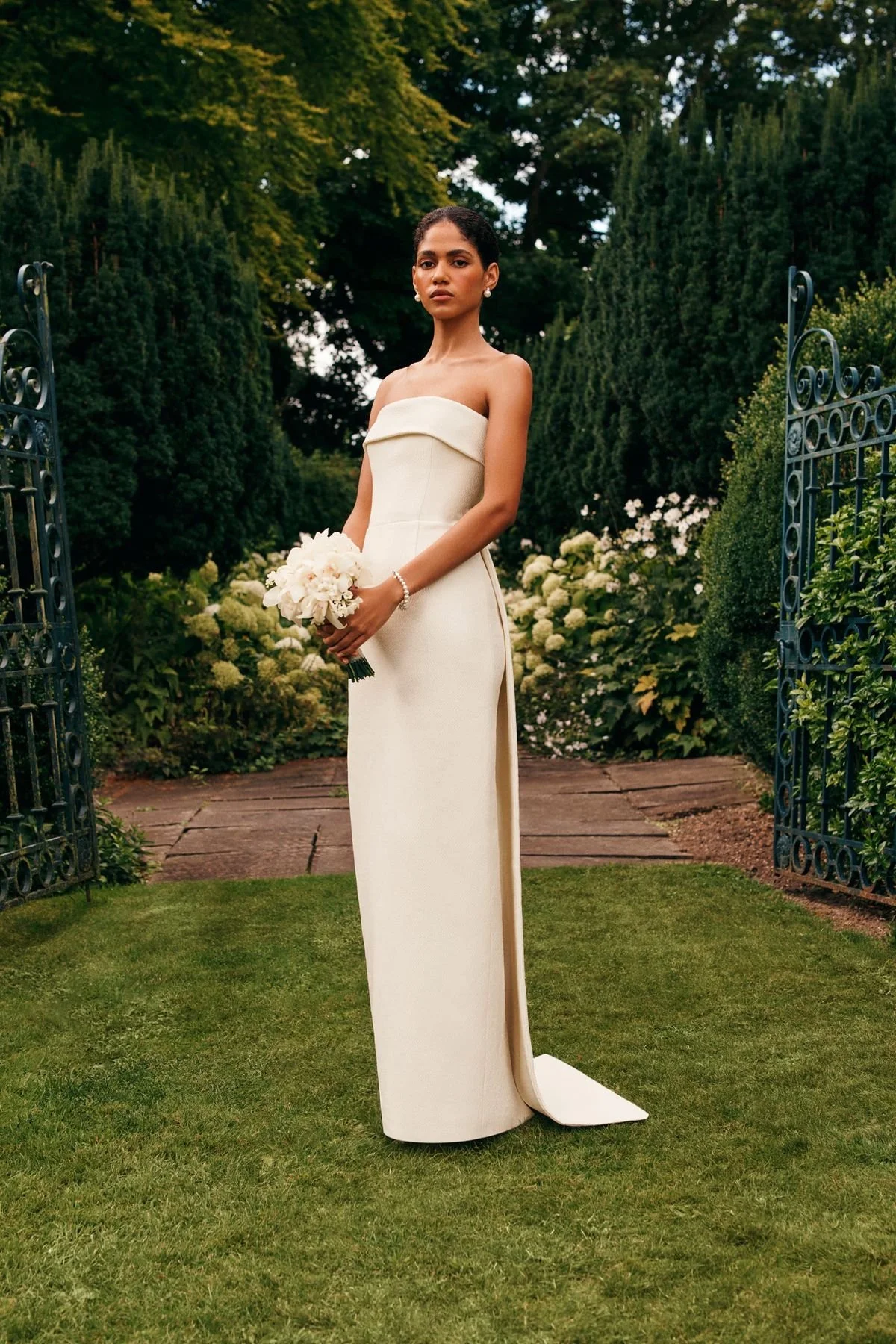 Modern bride in a simple strapless wedding dress holding white florals in an outdoor garden setting in Phoenix Arizona