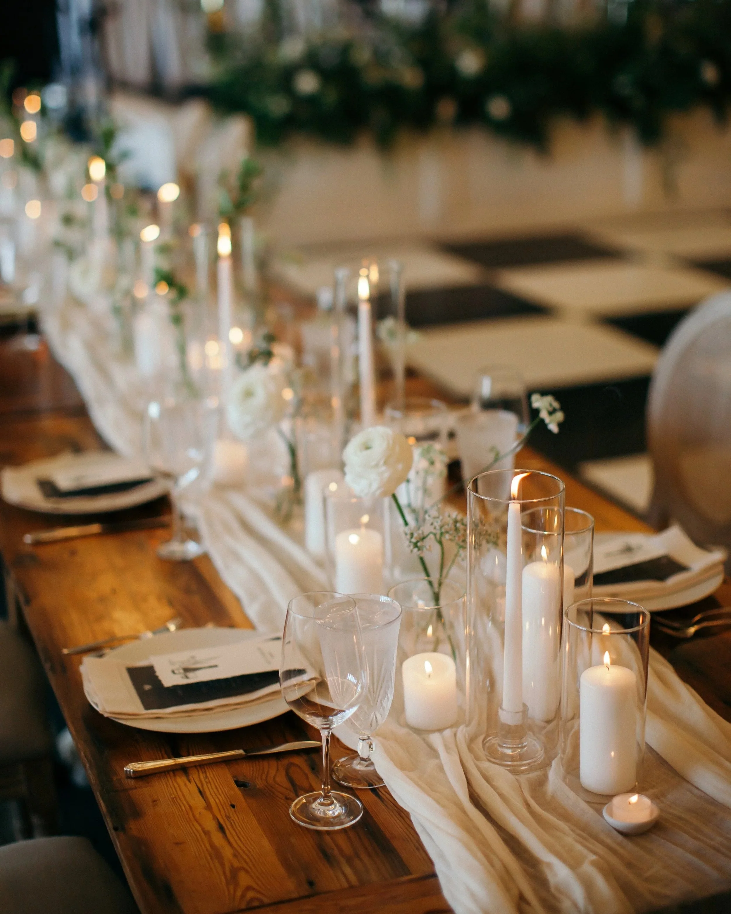 Elegant wedding reception table with white florals, glass candles, and linen runner at The Edgewater Hotel in Madison, WI.
