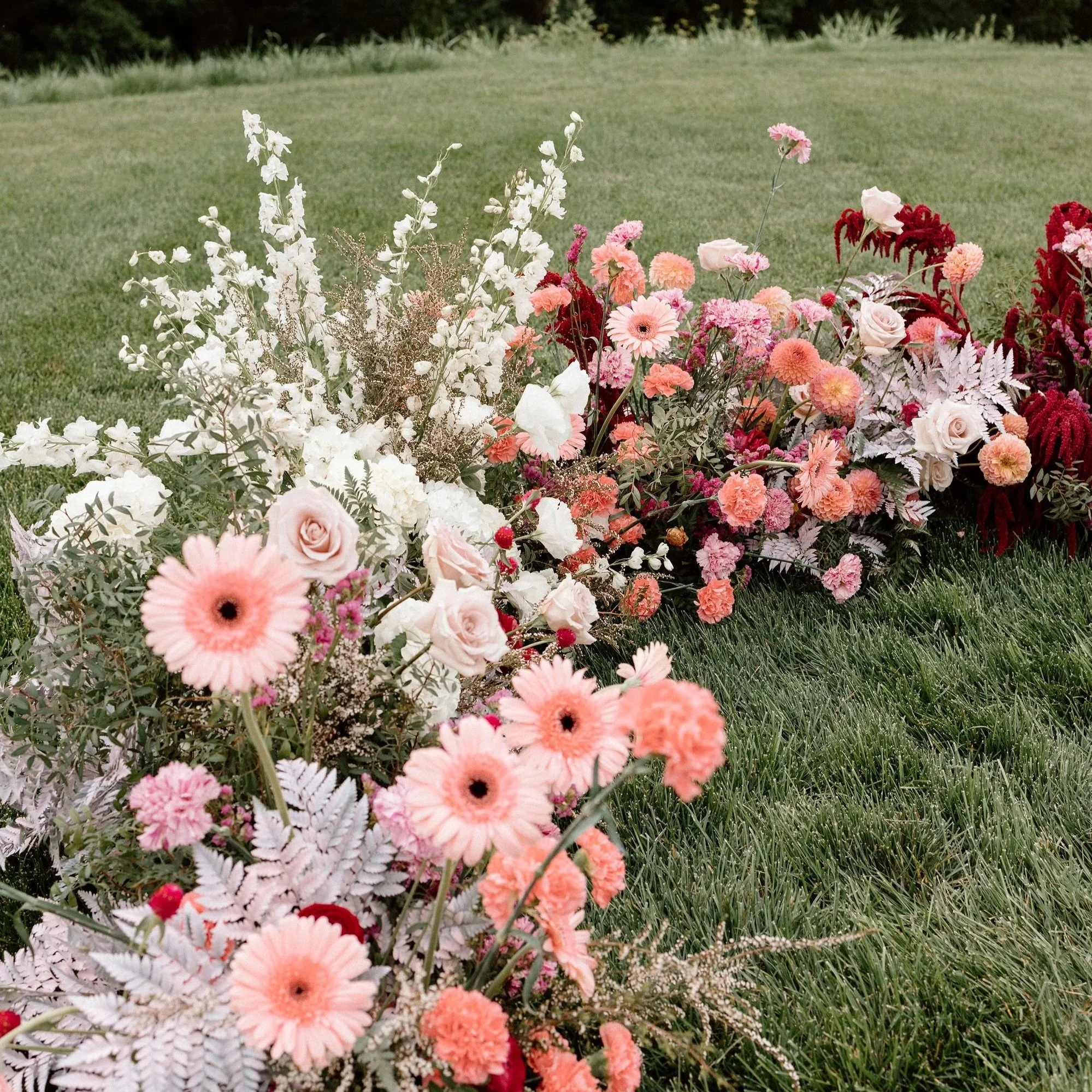 Colorful ceremony ground floral installation designed by 1209 Creative for a Milwaukee Wisconsin wedding, featuring blush, coral, and garden style blooms