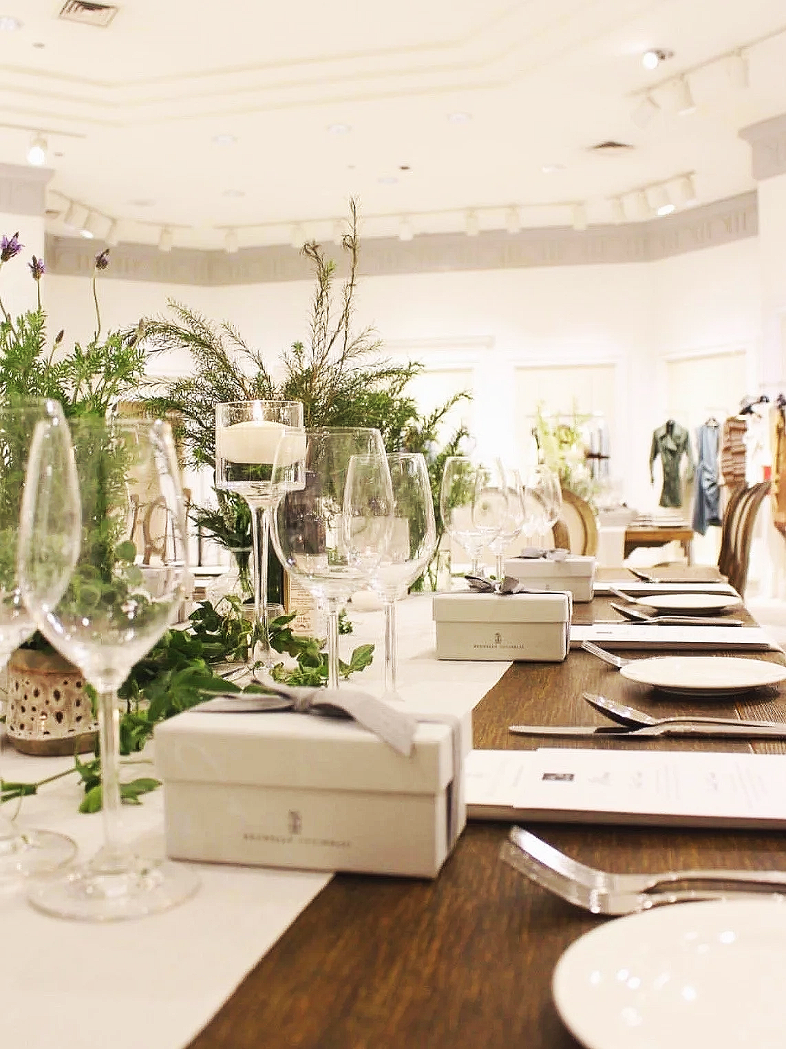 Event space with long tables decorated with flowers and candles, string lights hanging from the ceiling, a dartboard, and a staircase leading to a second level.