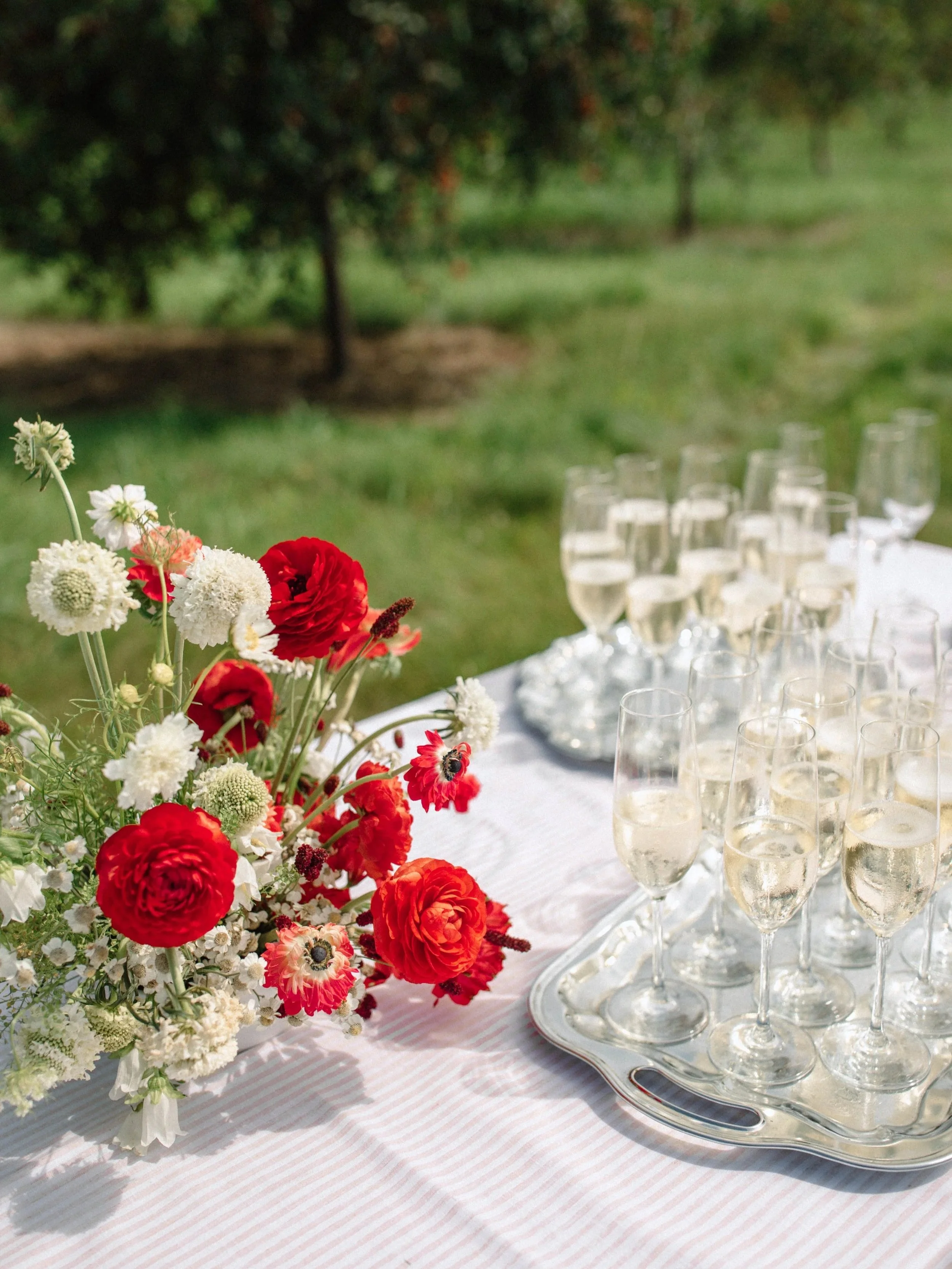 Red and white wedding floral arrangement on champagne table at cherry orchard wedding in Ellison Bay Door County Wisconsin by 1209 Creative florist