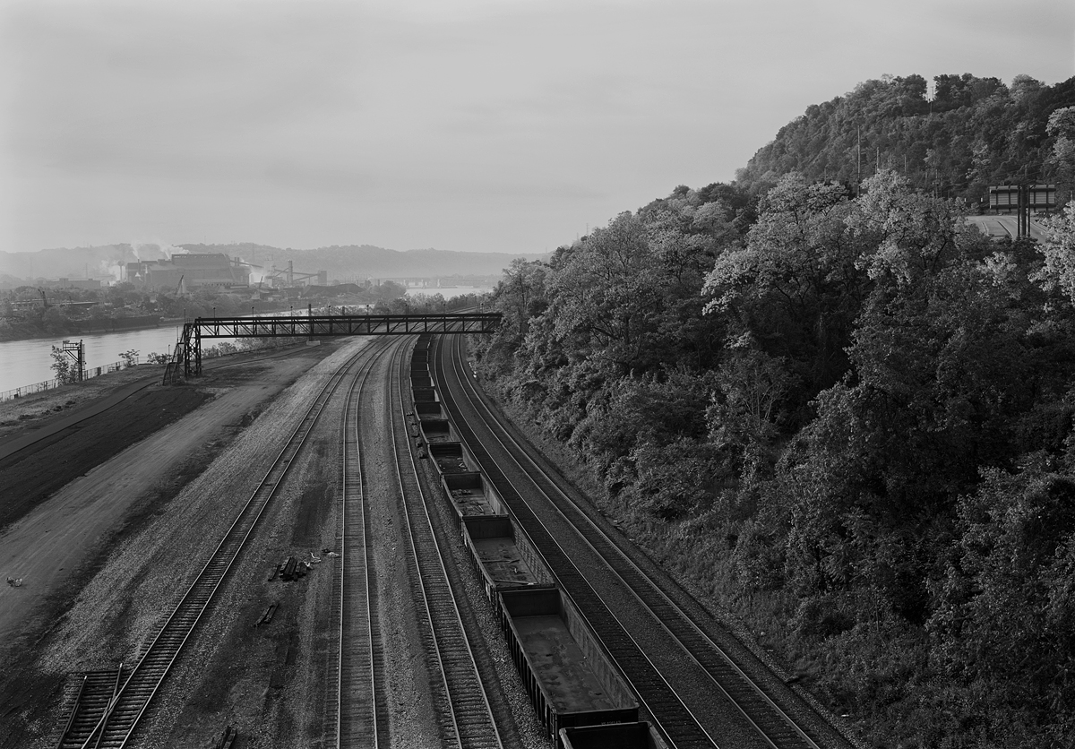 View southeast from the Rankin Bridge of the Mon Line and Union Railroad Interchange. From left to right, the first four tracks serve as the interchange leads for Munhall Yard, the last two are the main tracks of the Mon Line, now a double stack bypass for NS container trains with clearance issues on the mainline through Pittsburgh proper. Note the US Steel Edgar Thompson Works in the background in the industrial town of Braddock across the Monongahela River.