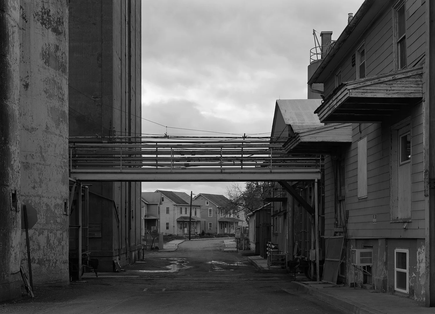 Former Milling Complex of the Wheatena Company, ConAgra and finally Homestat Farms Ltd located off Second Street in Highspire Pennsylvania. The facility straddles Jury St, in this view looking West. To the right (North) is the milling buildings and offices, the left (South) are the storage silos. The dwellings in the background are typical of the area, resembling company homes from the nearby former Bethlehem Steel Steelton Plant. If one looks carefully there is a former Chessie Covered hopper tucked away to the left of the grade crossing in the center foreground.