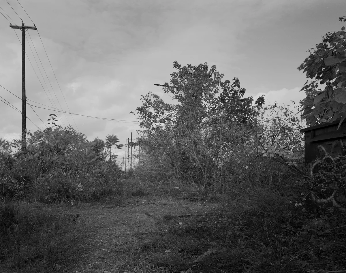Former location of J tower and the crossing of the Cumberland Valley Railroad and Northern Central Railway looking east. Note the catenary towers on the Cumberland Valley bridge in the distant center. The relay case in the right foreground supplemented Lemo tower some time in the early 1980s .
