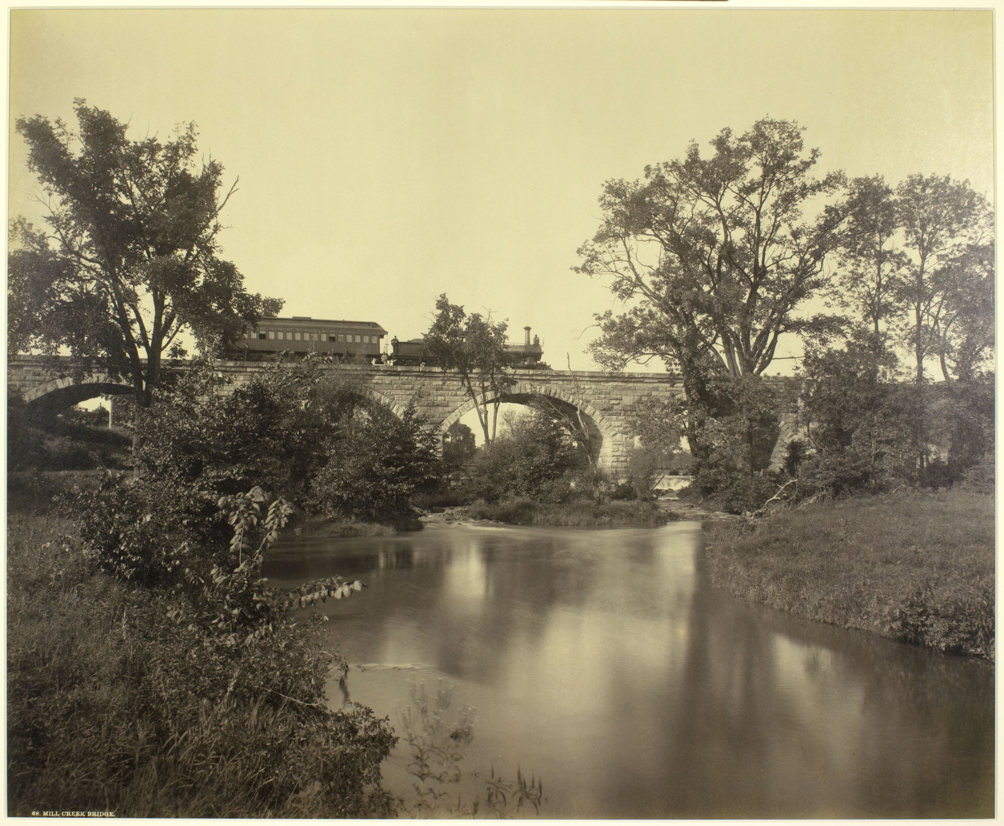 Plate 68: Mill Creek Bridge. Facing the southern facade of a virtually brand new bridge spanning Mill Creek, photographer William H. Rau frames the special photography train staged on the bridge. Very little has changed here with the exception of the concrete reinforcement and catenary towers as seen by the inset photo below taken in 2013. William H Rau image collection of American Premier Underwriters, Inc.