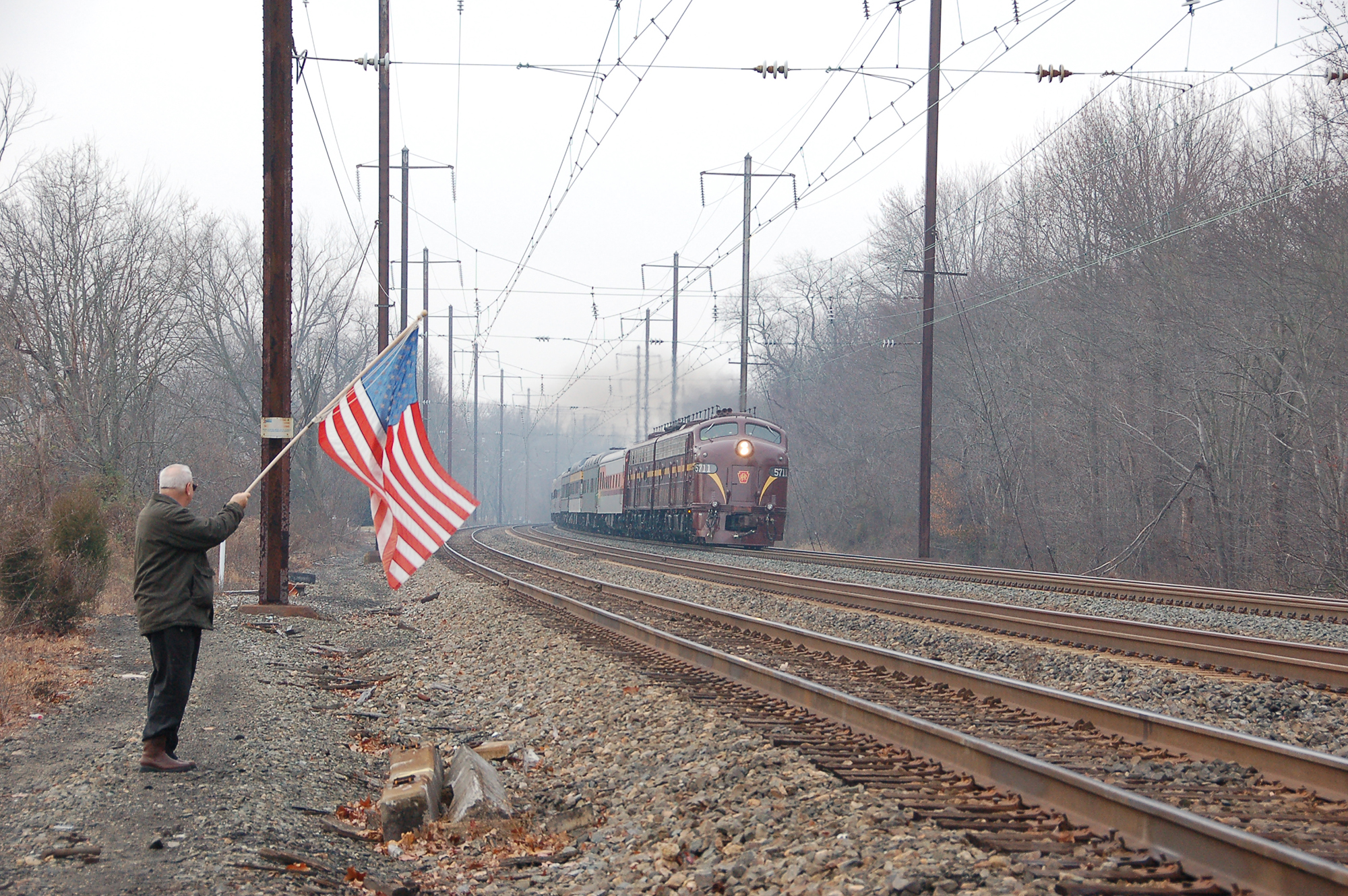 Passing through Chase Maryland, on Amtrak's Northeast Corridor, the Liberty Limited, powered by Bennett Levin's 2 E8 locomotives pulling 19 private cars carrying military personnel wounded in the service of our country, is enroute from Washington, D.C. to the Army-Navy football game in Philadelphia, PA. Waving a flag that had flown over our nation's capitol, retired Army Reserve Colonel Lex Bishop lets the military personnel aboard the special train know that their service & sacrifice is appreciated. Photography by Don Kalkman Jr. 