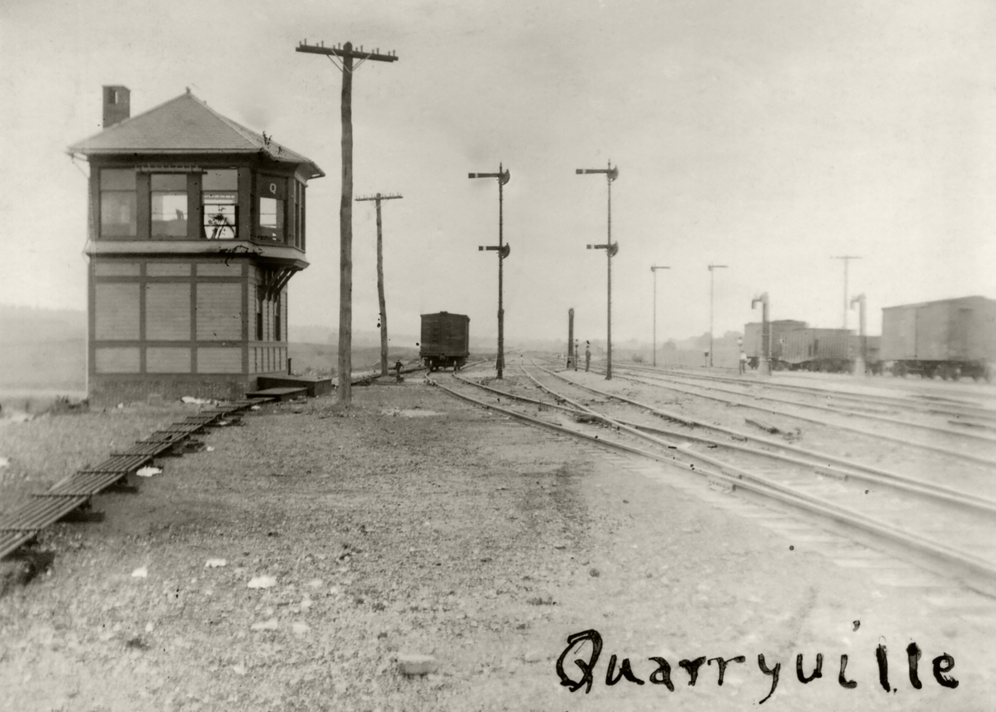 This 1906 view shows the wood frame tower at Quarryville (Milepost 10.8), the first interlocking tower west of Parkesburg. "Q" had control over the two main tracks and four additional sidings to manage helper movements assisting trains to Mars Hill Summit. Additionally four water columns were available to top off steam locomotive tenders on their journey east or west. Image collection of William L. Seigford