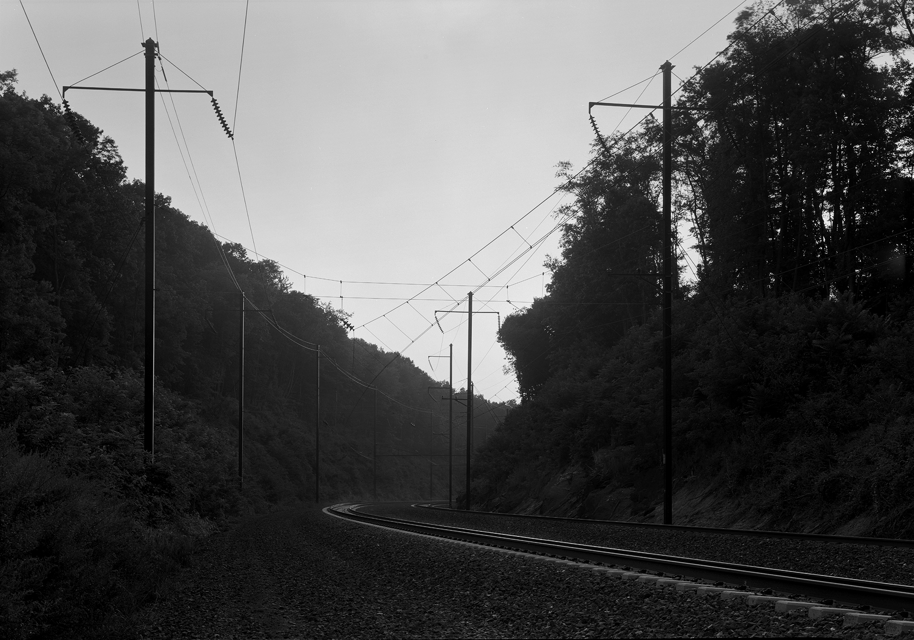In this westward view of the North Bend Cut, near the vicinity of Shuman's image, we see two tracks remain, now under the guise of the Commonwealth funded Keystone Corridor, operated by Amtrak. The contemporary railroad landscape without the context of historical images can still present a beautiful study in light and shadow, in this modern view. 