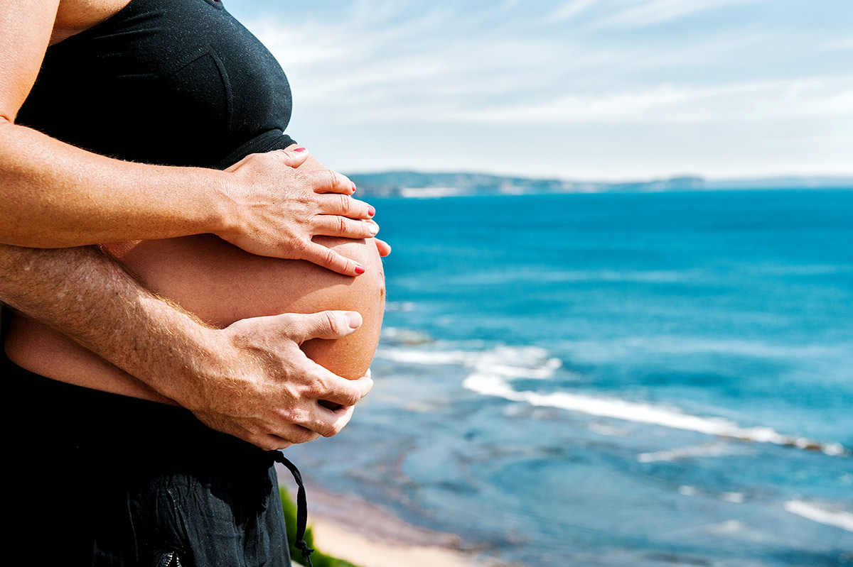 Bare pregnant belly with Collaroy beach in the background