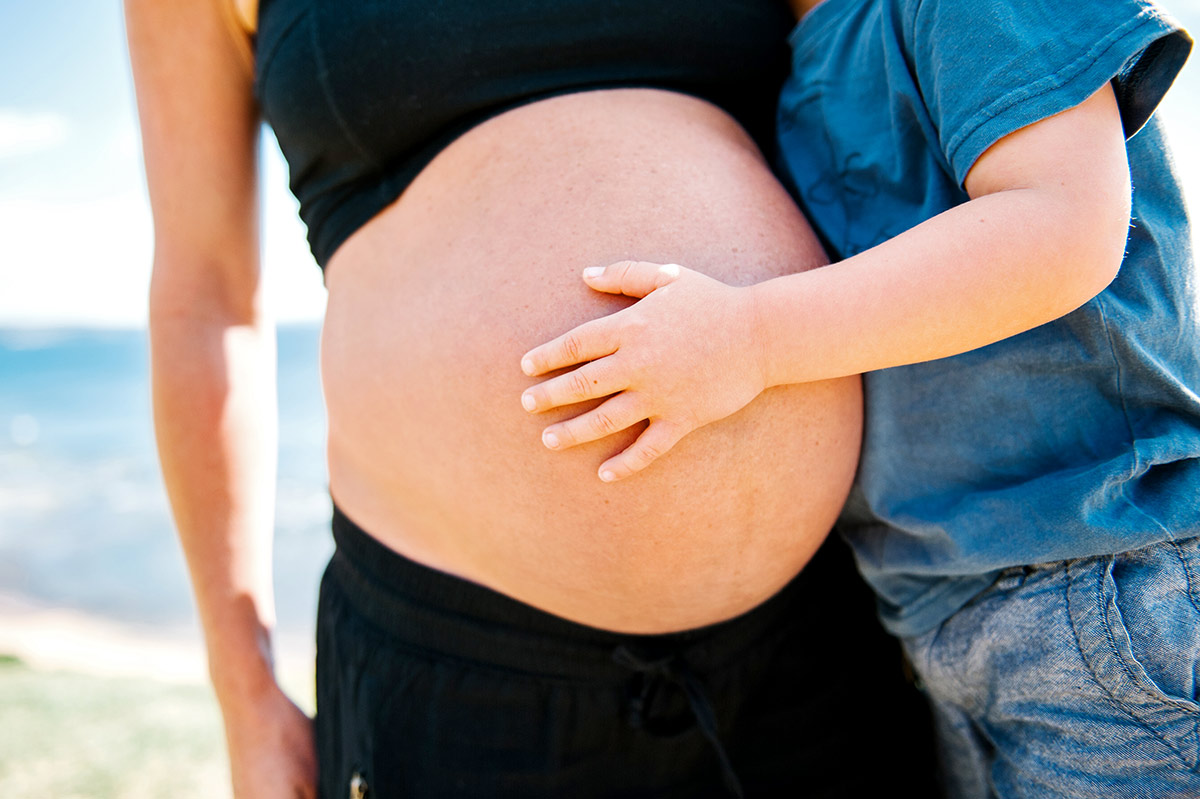 Toddler's hand on mum's pregnant belly