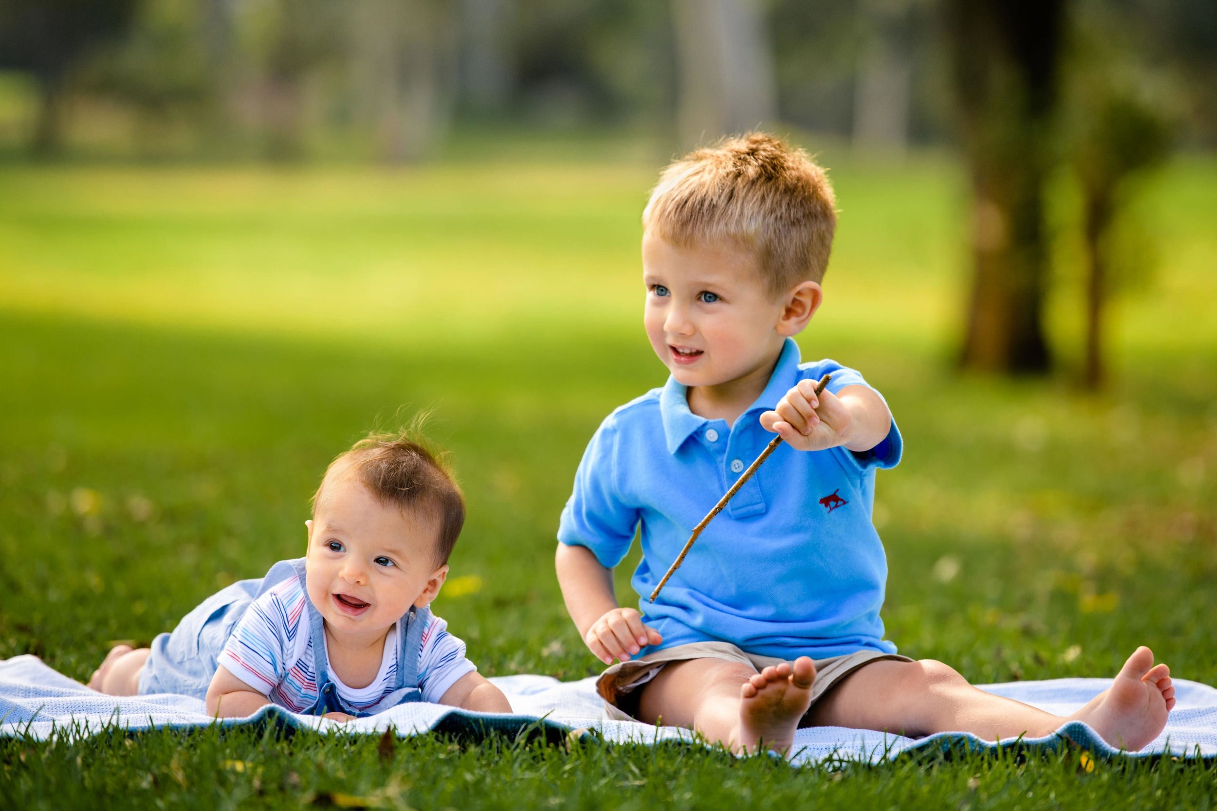 Brothers on a picnic blanket with park in the background