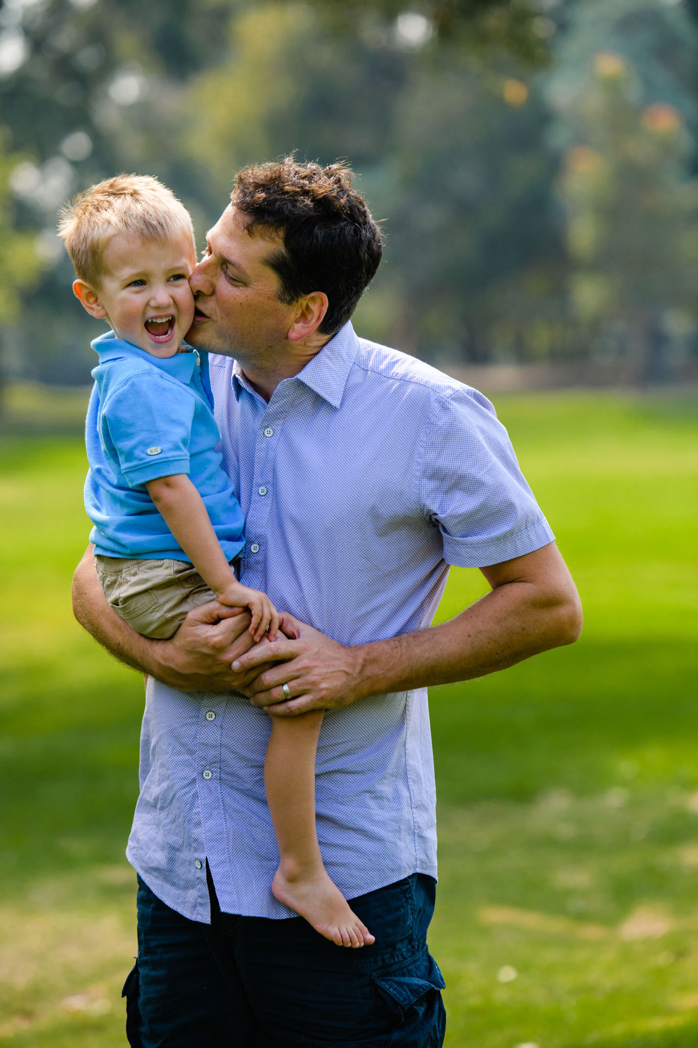 Toddler laughing as dad kisses him on the cheek