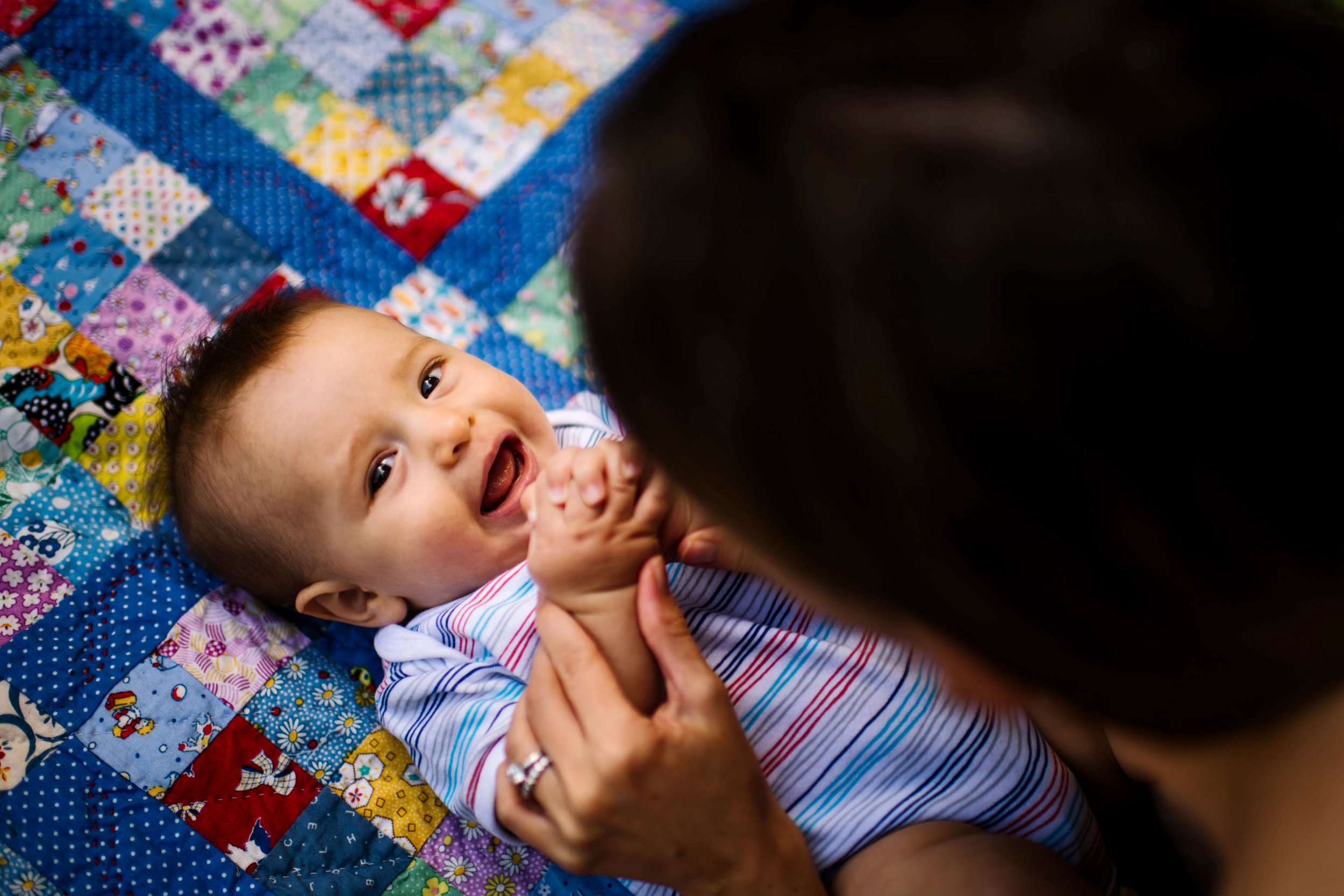 Baby smiling while being tickled by mum