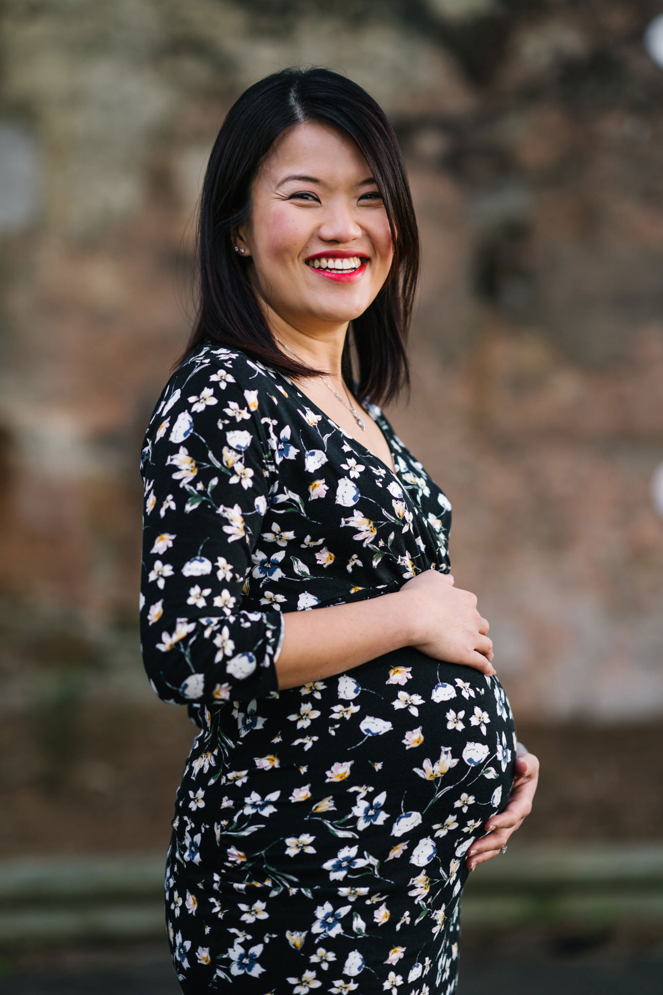 Pregnant woman in floral dress looking down at her belly