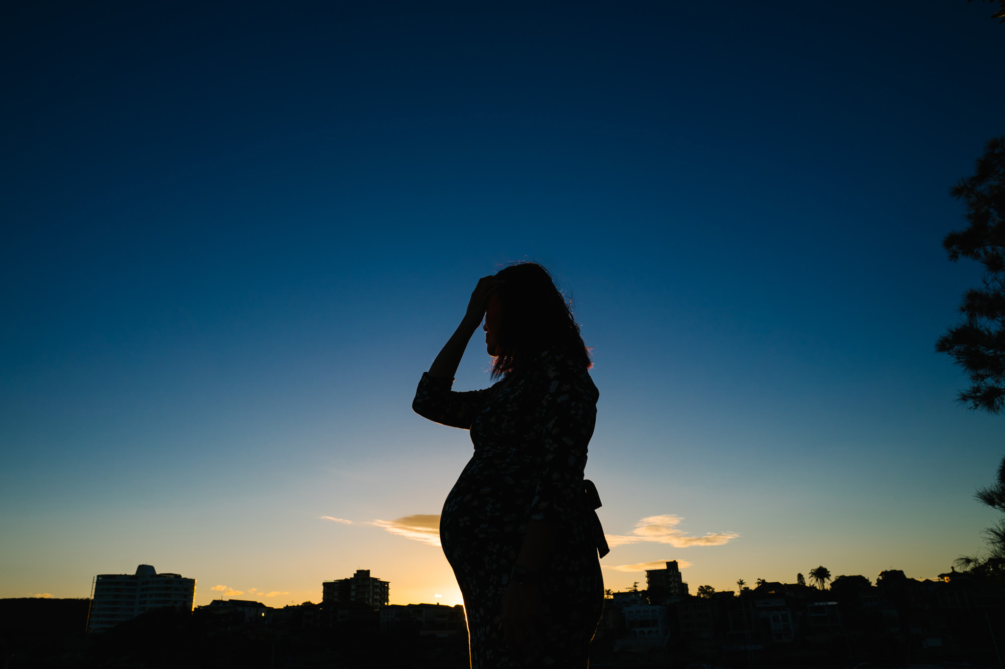 Silhouette of pregnant woman with sunset sky in the background