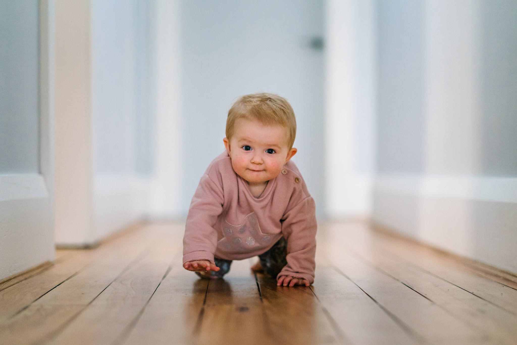 Baby crawling down hallway with cute look on her face