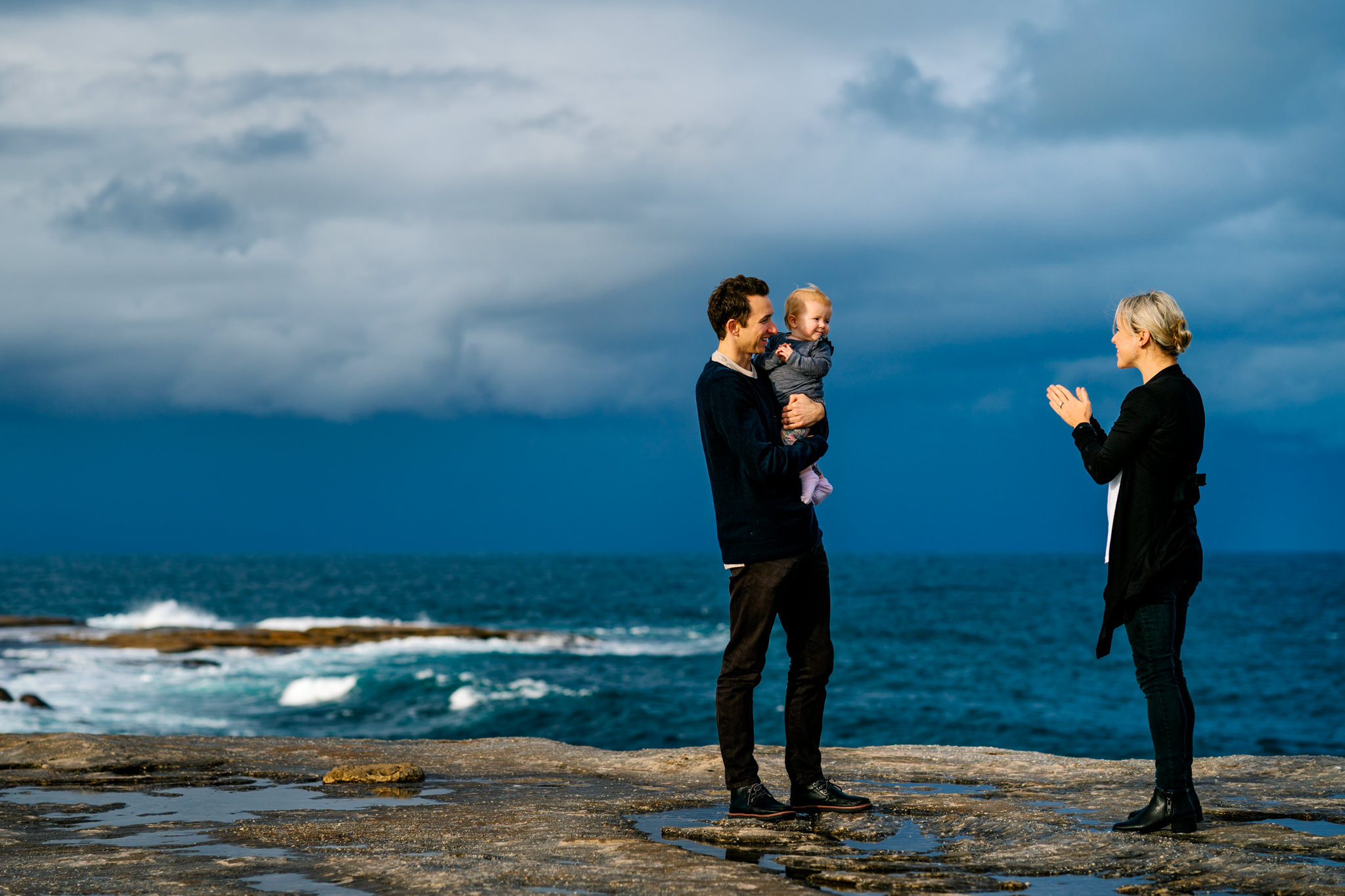 Parents and baby playing with Coogee beach, NSW in the background
