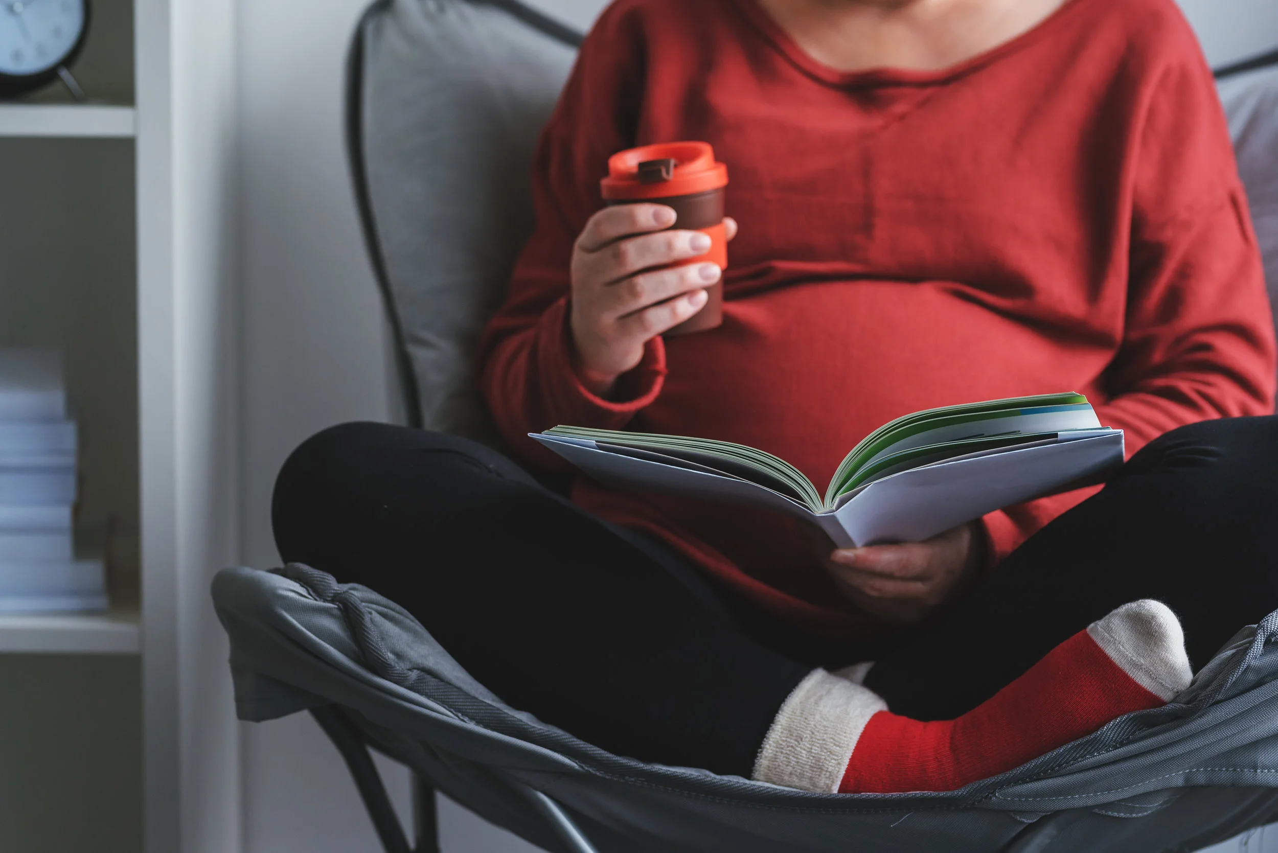 pregnant-woman-reading-book-in-living-room-PZQVXGG.jpg