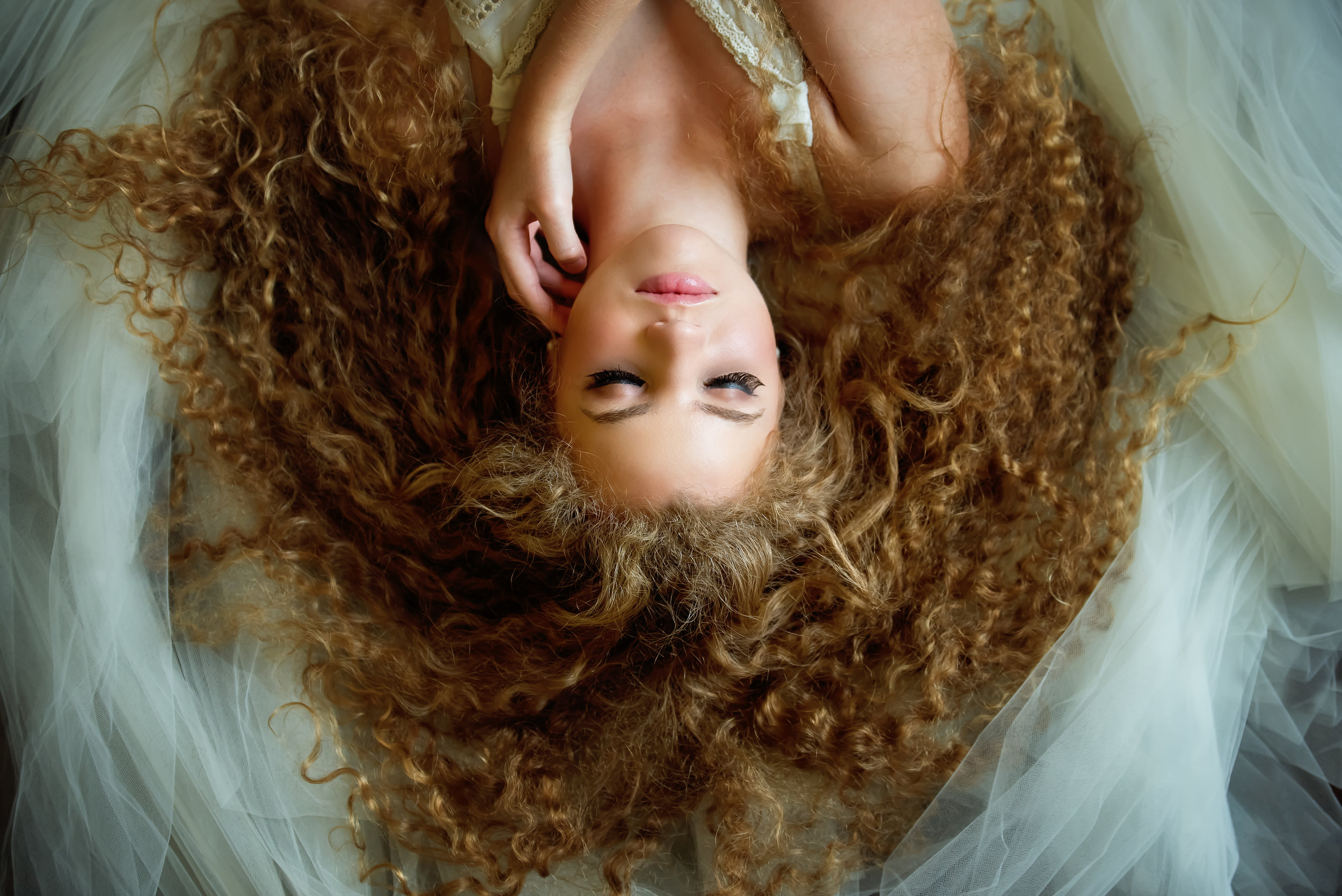  Headshot from above of a woman with curly hair lying on a white veil. Douglas County 