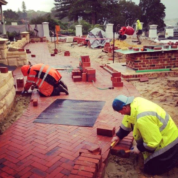 Header Course installation in Peppermint Grove. These recycled red bricks have been laid 'on-edge' and the header courses are being installed on a concrete bed to secure them in place and prevent movement over time.