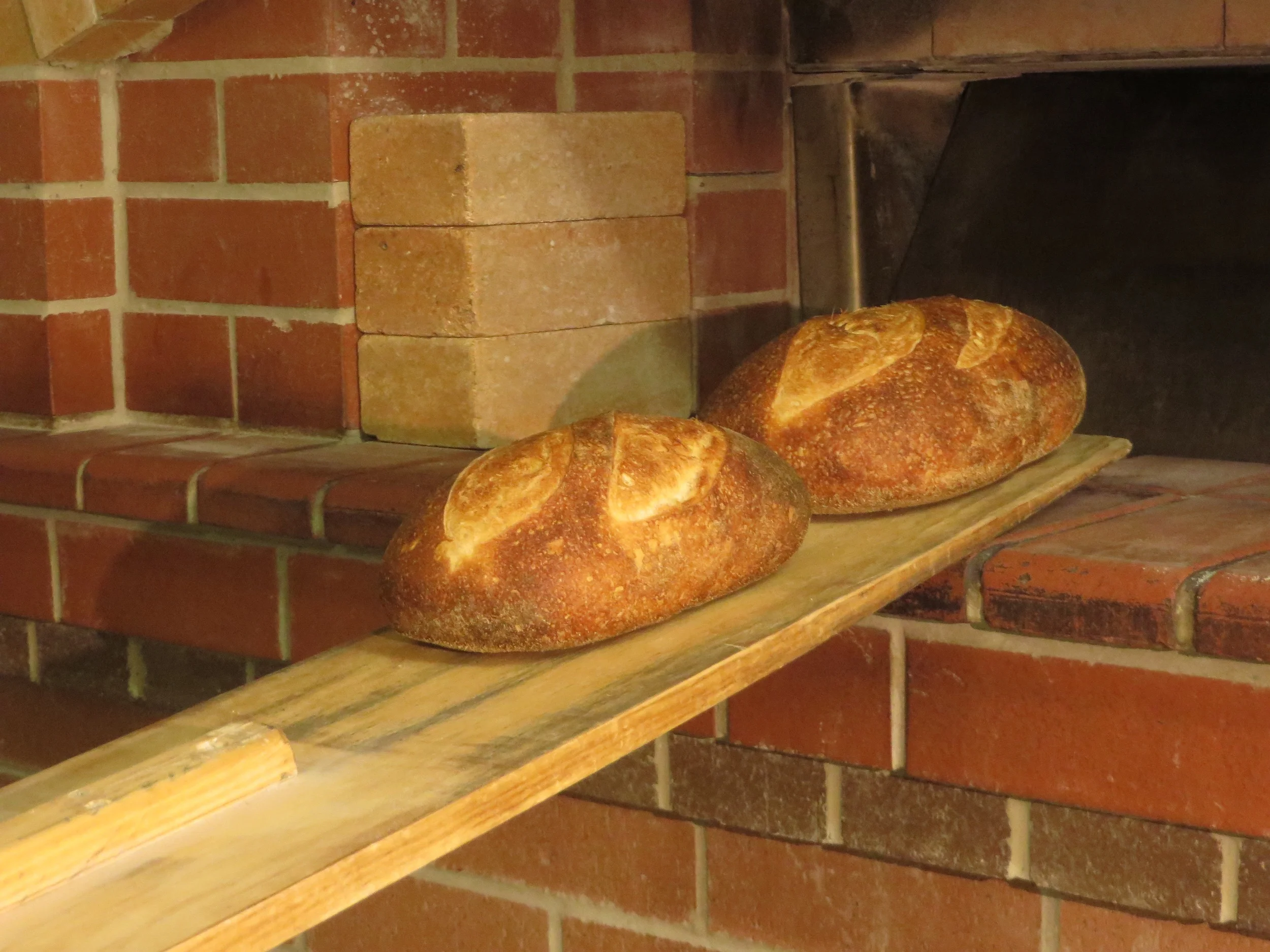 The oven is unloaded using the peel. The bread is then allowed to cool. The bake usually takes between 12 - 14 hours from the time the first doughs are made to the time the last loaf comes out of the oven. As a micro bakery, a single pair of hands is involved every step along the way. The baker that starts the bake finishes the bake.