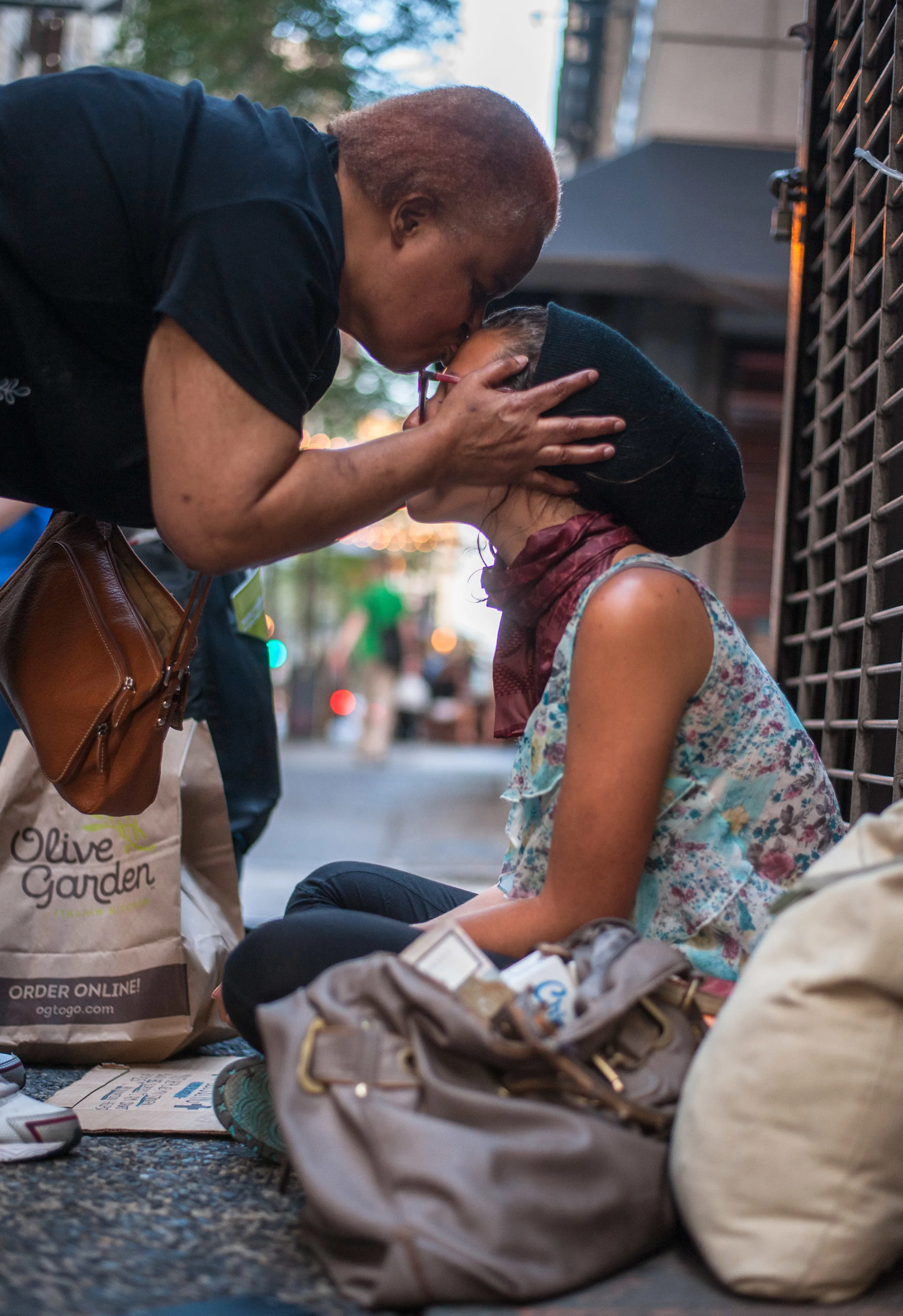Cathy Kennedy leans to give Angel Weber a kiss on the forehead after giving her a few dollars on the corner of Juniper and Chestnut Street after a passerby told her she "should just get a job" on Wednesday, July 30th, 2015. Weber has been homeless for two years after she lost her business located in South Philadelphia after a decline in the economy at that time. 