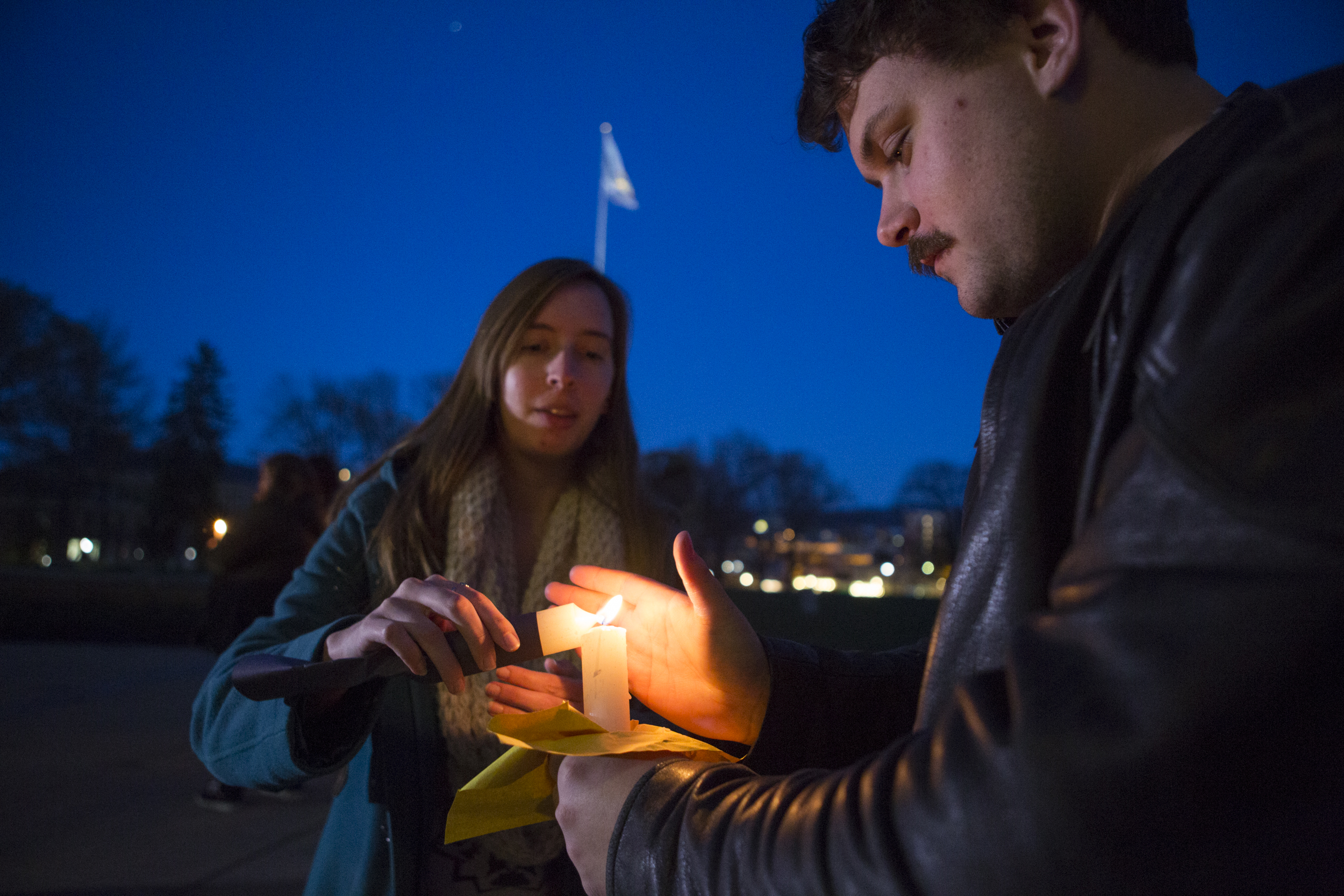 Sylvia Kitterman (senior - IST), left, lights a candle for Conner Mangan (senior - energy, business and finance) to begin the Candlelight Vigil Against Global Violence on the steps of Old Main on Tuesday, March 29, 2016.