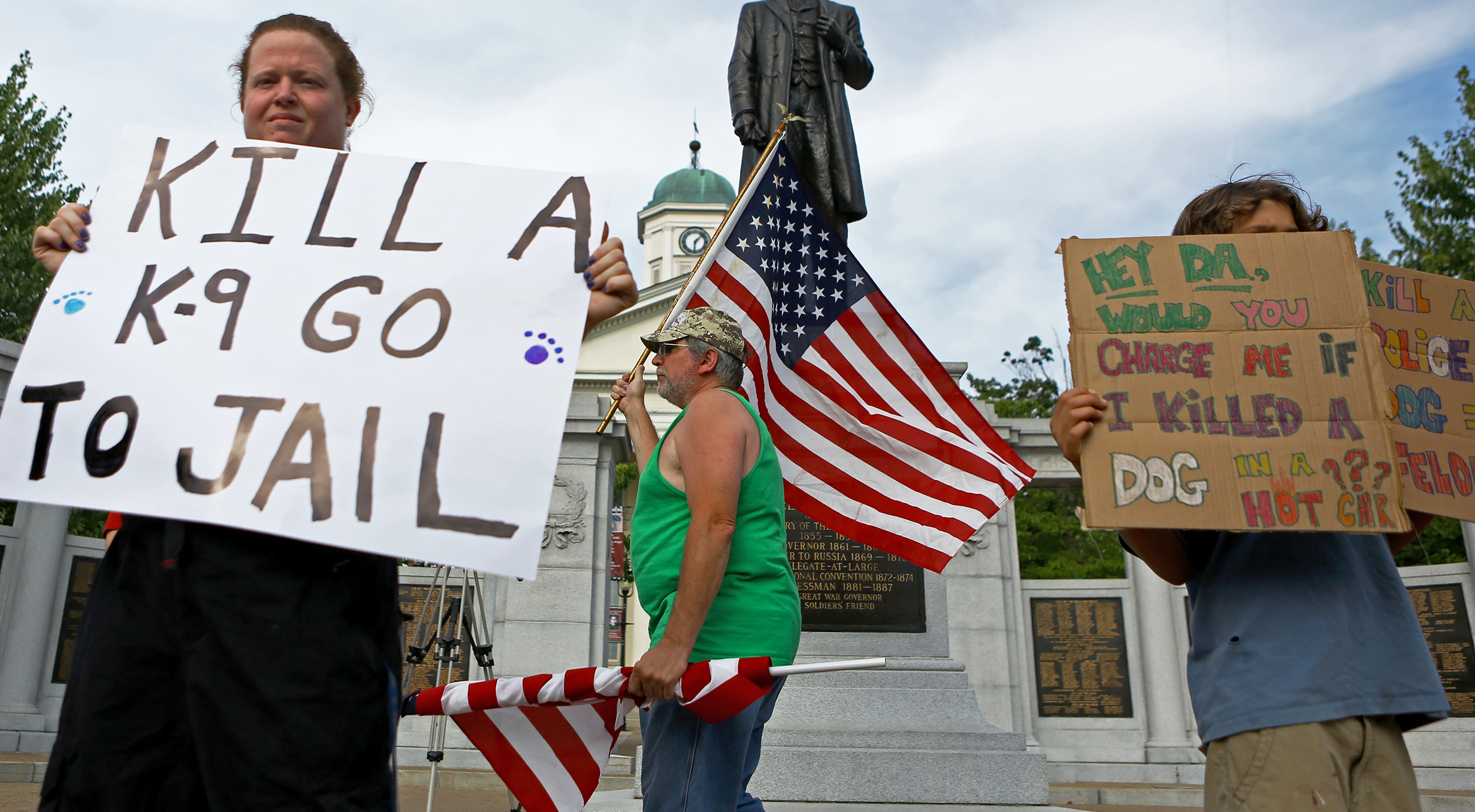 Tim Wian, center, of Phillipsburg flies the American flag as other Centre County residents hold signs on Allegheny Street in Bellefonte on Monday, July 18, 2016 calling for justice for Totti, a Department of Corrections drug detection dog that died after being locked in a hot car for over two hours.