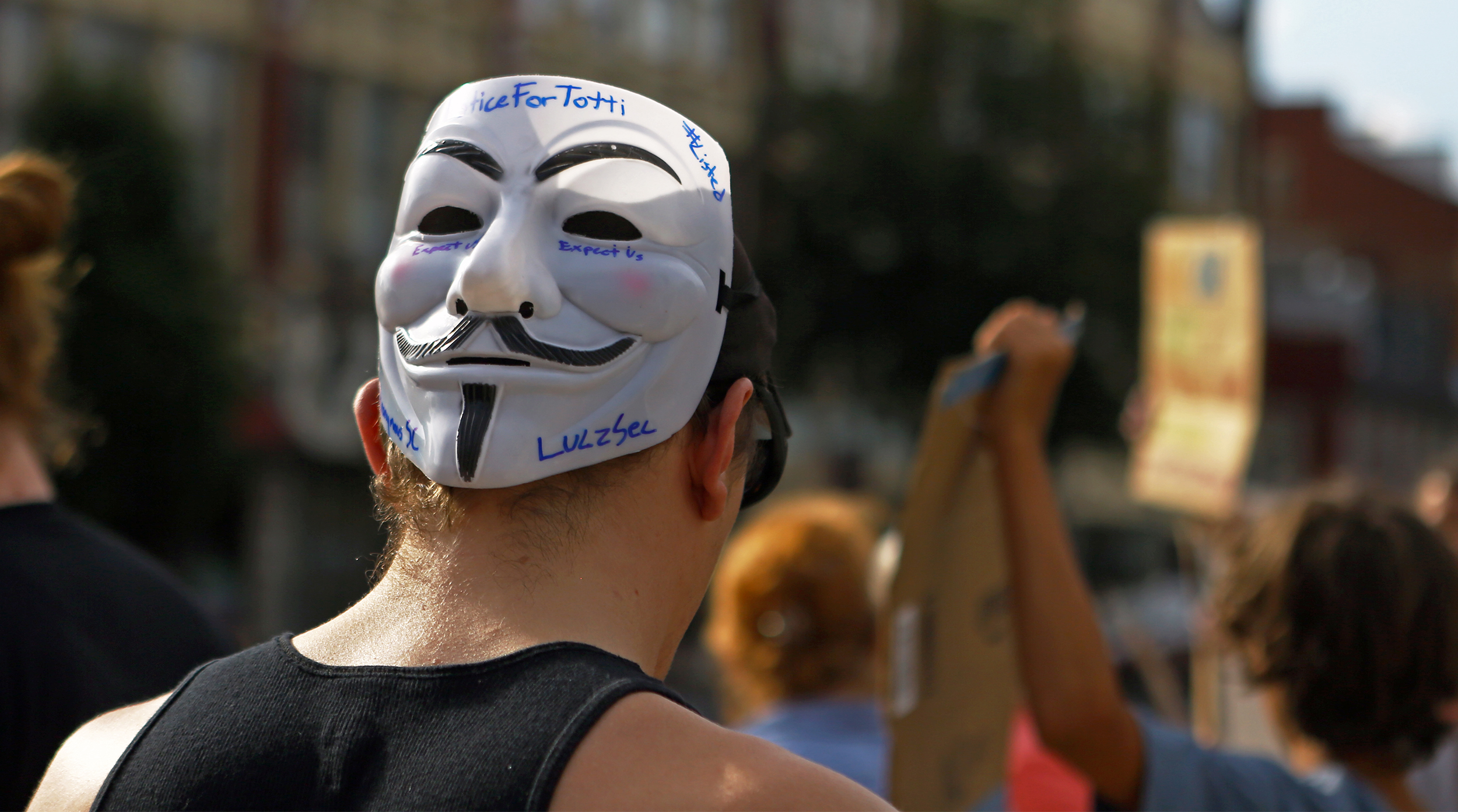 Justin Wian of Bellefonte wears a Guy Faux mask on the back of his head reading "Justice for Totti" as he joins the other Centre County residents in front of the Centre County courthouse on Monday, July 18, 2016 calling for justice for Totti, a Department of Corrections drug detection dog that died of heat exposure after being locked in a squad car for over two hours.