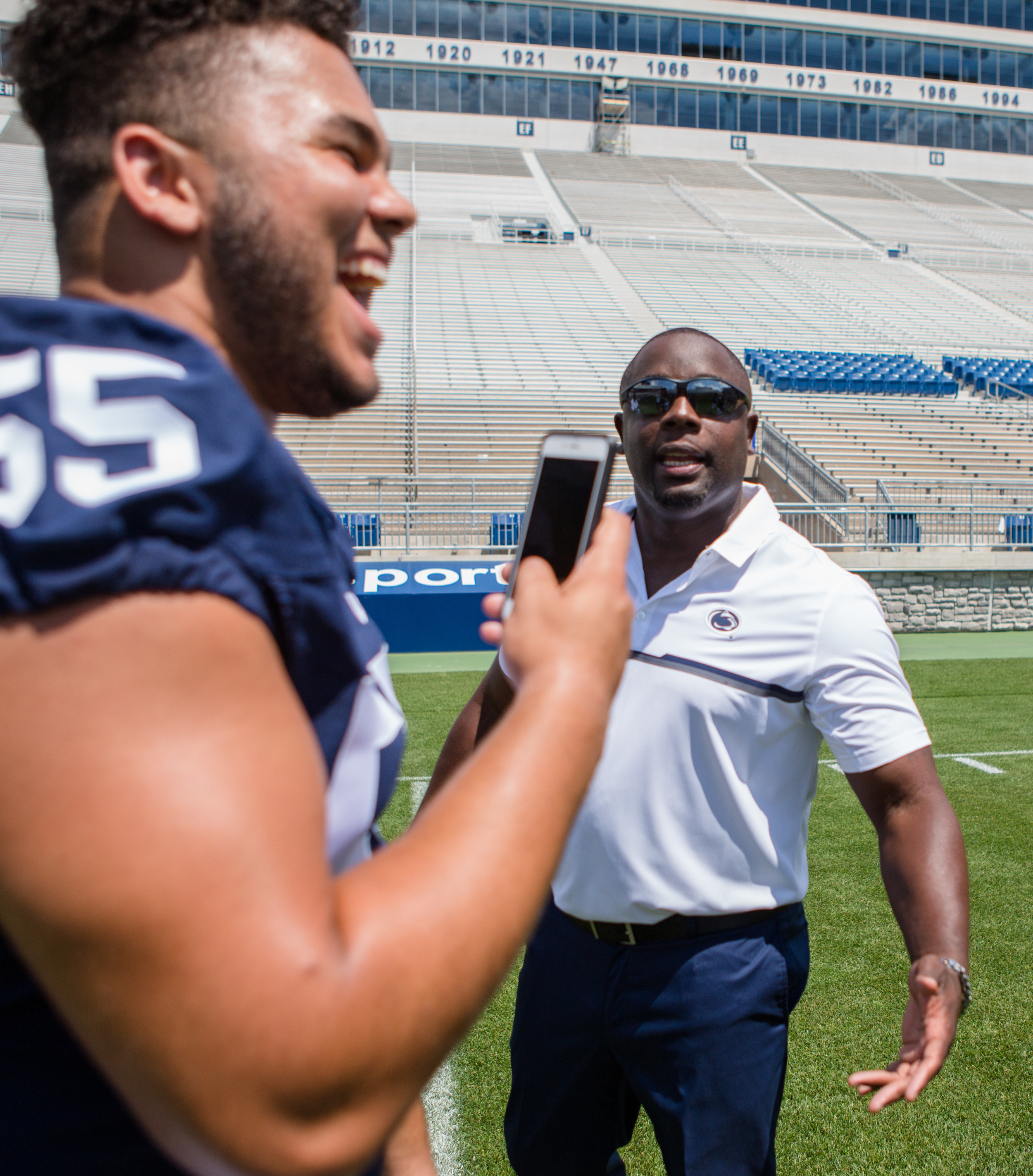 Freshman defensive tackle Antonio Shelton laughs while recording a Snapchat of defensive line coach Sean Spencer during the football team's photo day on the field of Beaver Stadium on Sunday, Aug. 7, 2016.