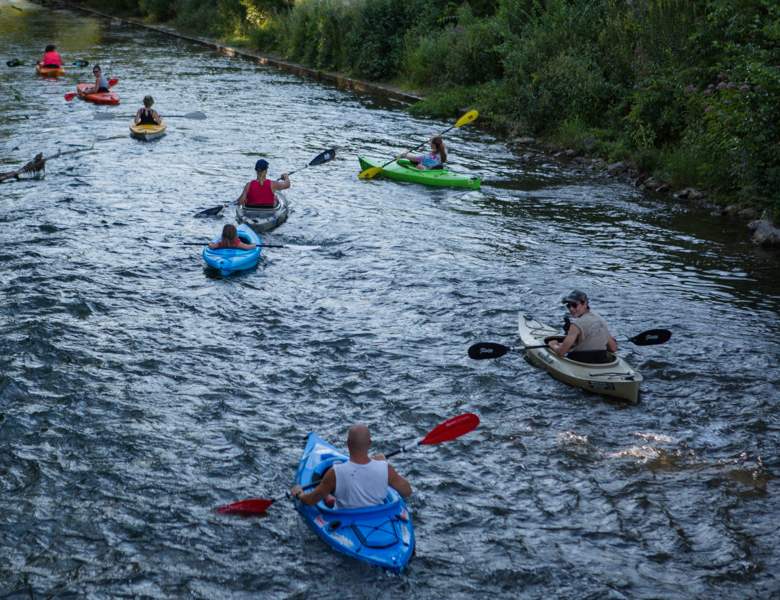 Members of the Rossman and Brown families of Howard paddle their kayaks down Spring Creek after launching from the newly opened waterfront walkway on Sunday, Aug. 7, 2016.