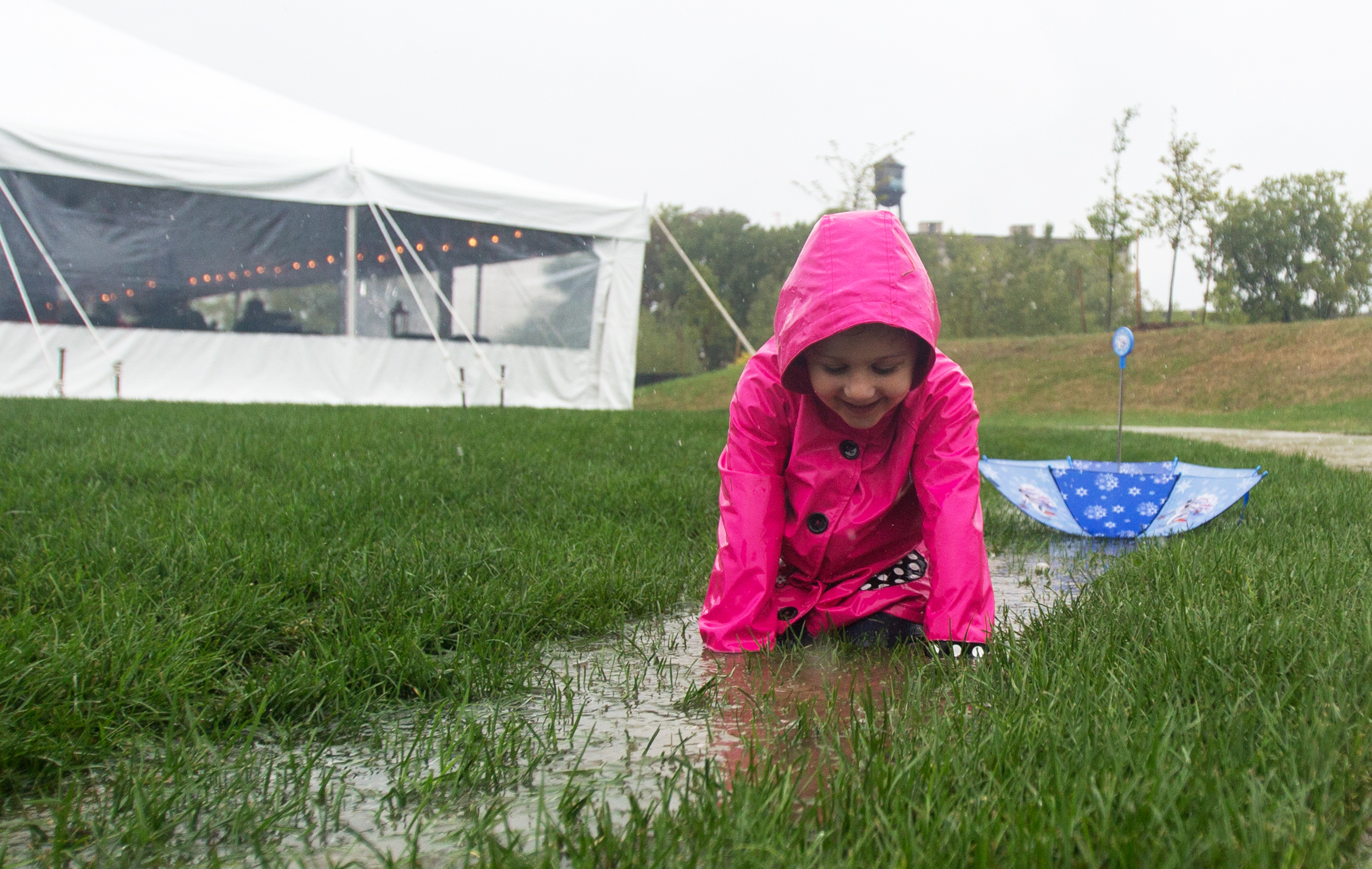 Sloan Wilkenson, 4, of Toledo plays in one of the puddles created by the steady rain while visiting the newly opened Middlegrounds Metropark in downtown Toledo with her father and brother on Saturday, Sept. 17, 2016. 