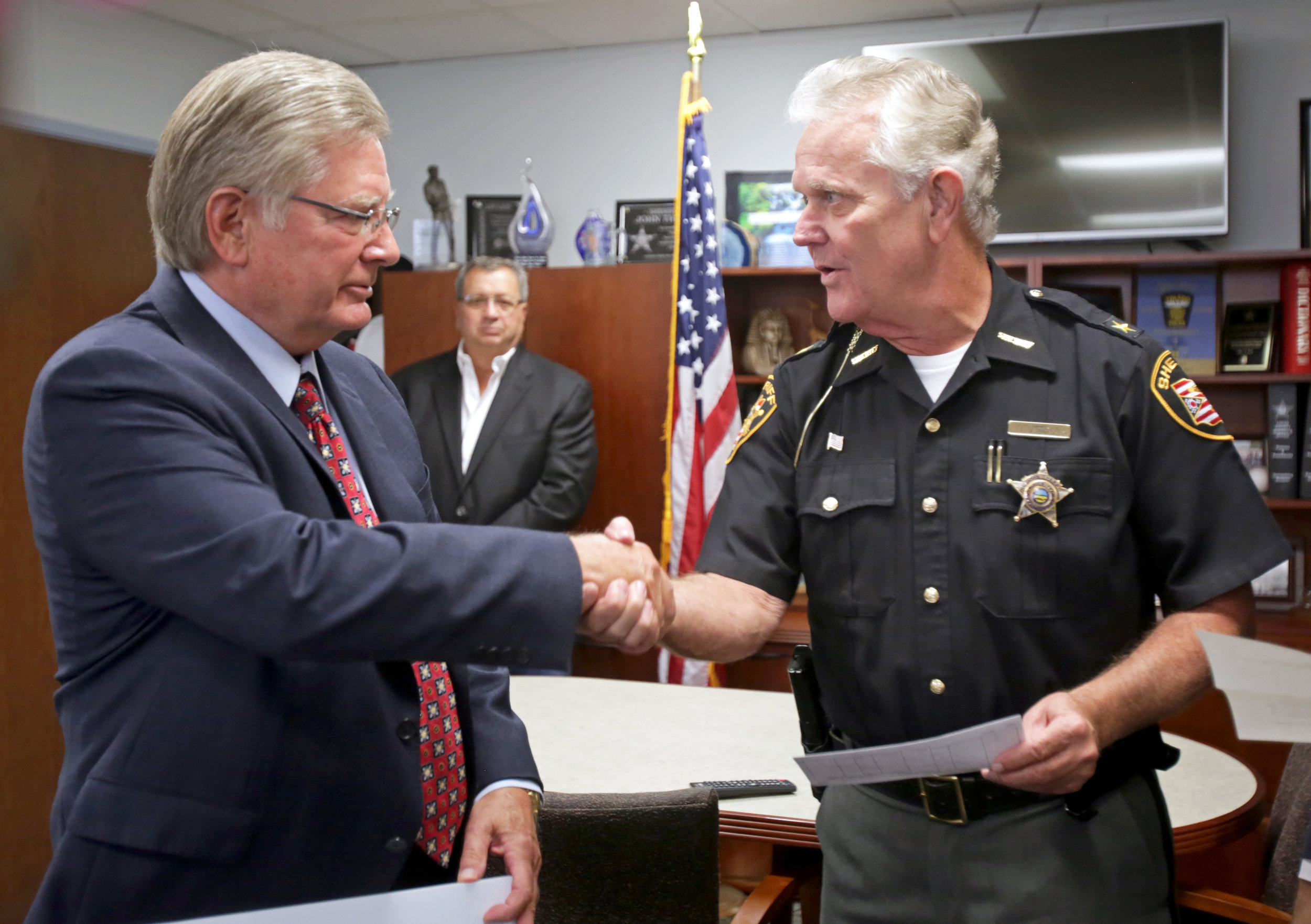 Lucas County sheriff John Tharp, right, shakes hands with Louisville Title CEO John Martin after the company presented the sheriff with a $10,000 check to support the operating costs of the Drug Abuse Response Team at the Lucas County Sheriff's Office in downtown Toledo on Tuesday, Sept. 27, 2016. 