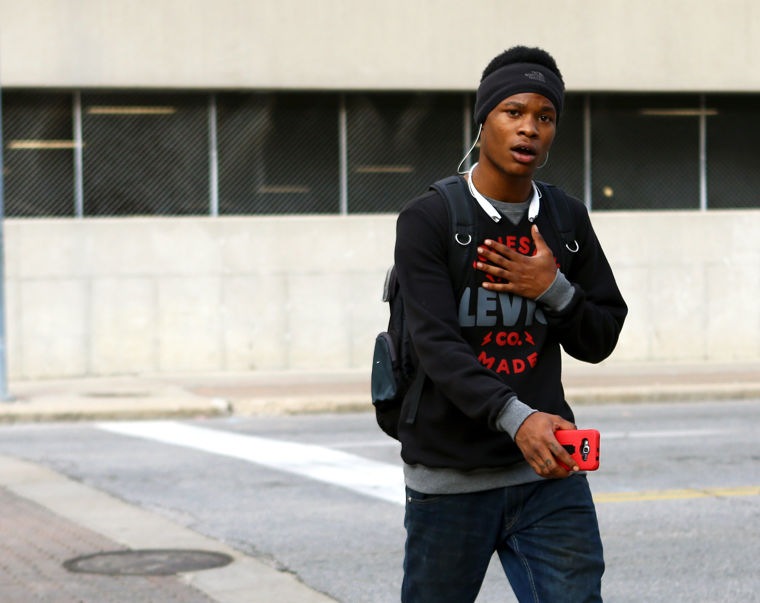 Breon Ellis sings along to his music while crossing Monroe St. on Huron St. in downtown Toledo on his way to start his shift at the Spaghetti Warehouse on Monday, Oct. 3, 2016. 