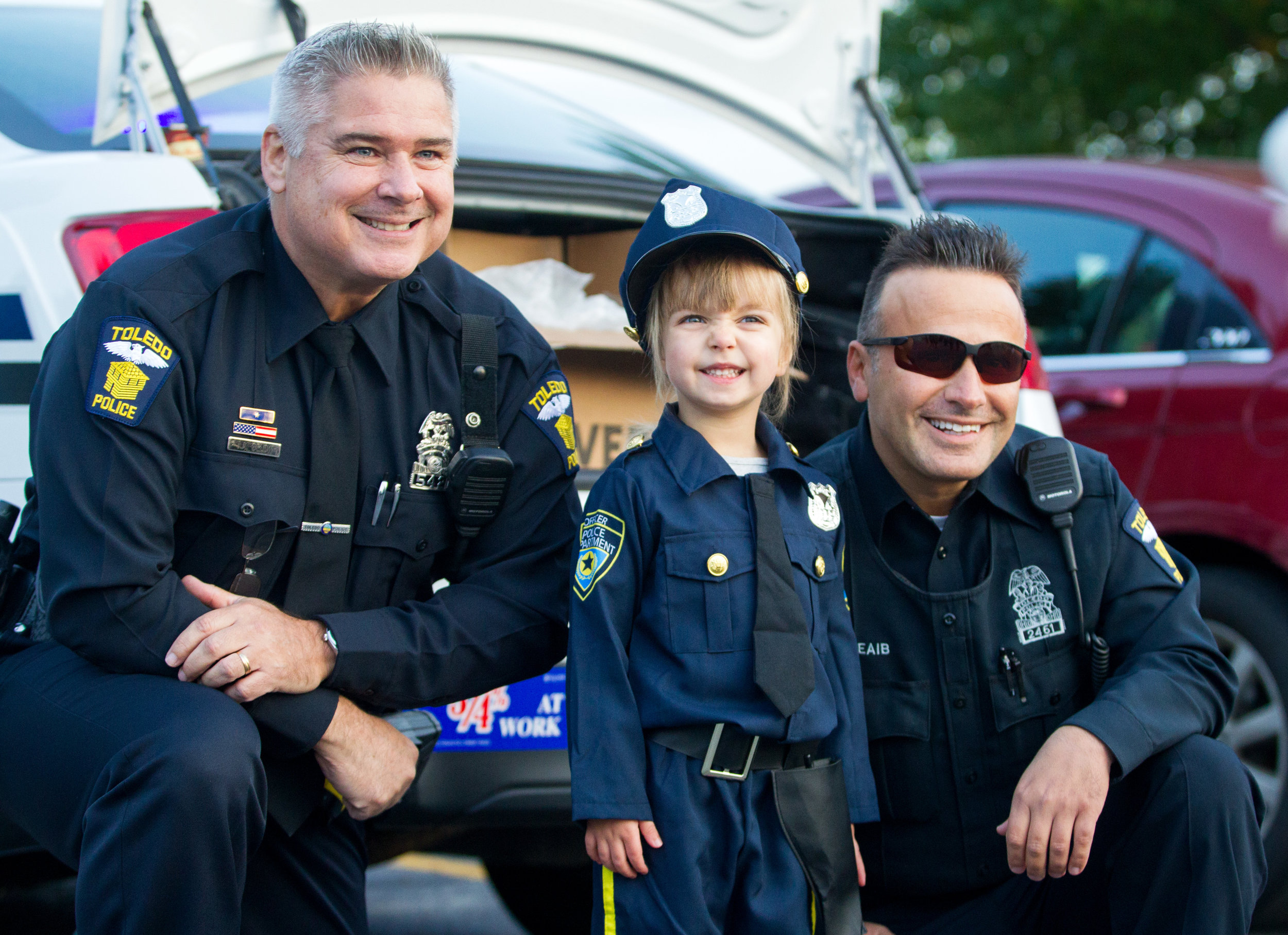 Toledo police officers Jim Below, left, and Hassane Cheaib, right, pose with Morgan Mahaney, 3, during the Winterfield Venture Charter Academy's Fall Festival at the school on Wenz Rd. in Toledo on Tuesday, Oct. 25, 2016.