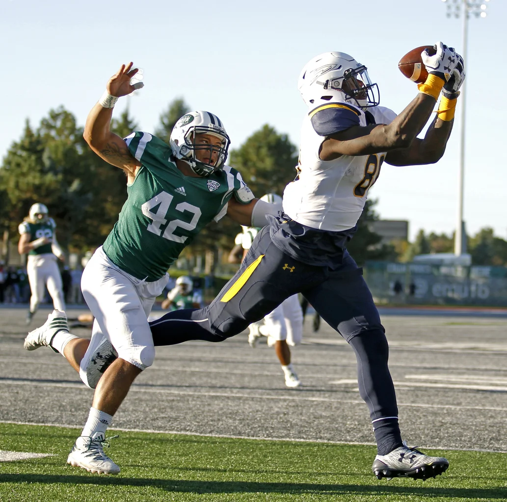  University of Toledo senior tight end Michael Roberts (80) completes a pass for a touchdown while under coverage from Eastern Michigan linebacker Derric Williams (42) during the football game at Rynearson Stadium in Ypsilanti on Saturday, Oct. 8, 20