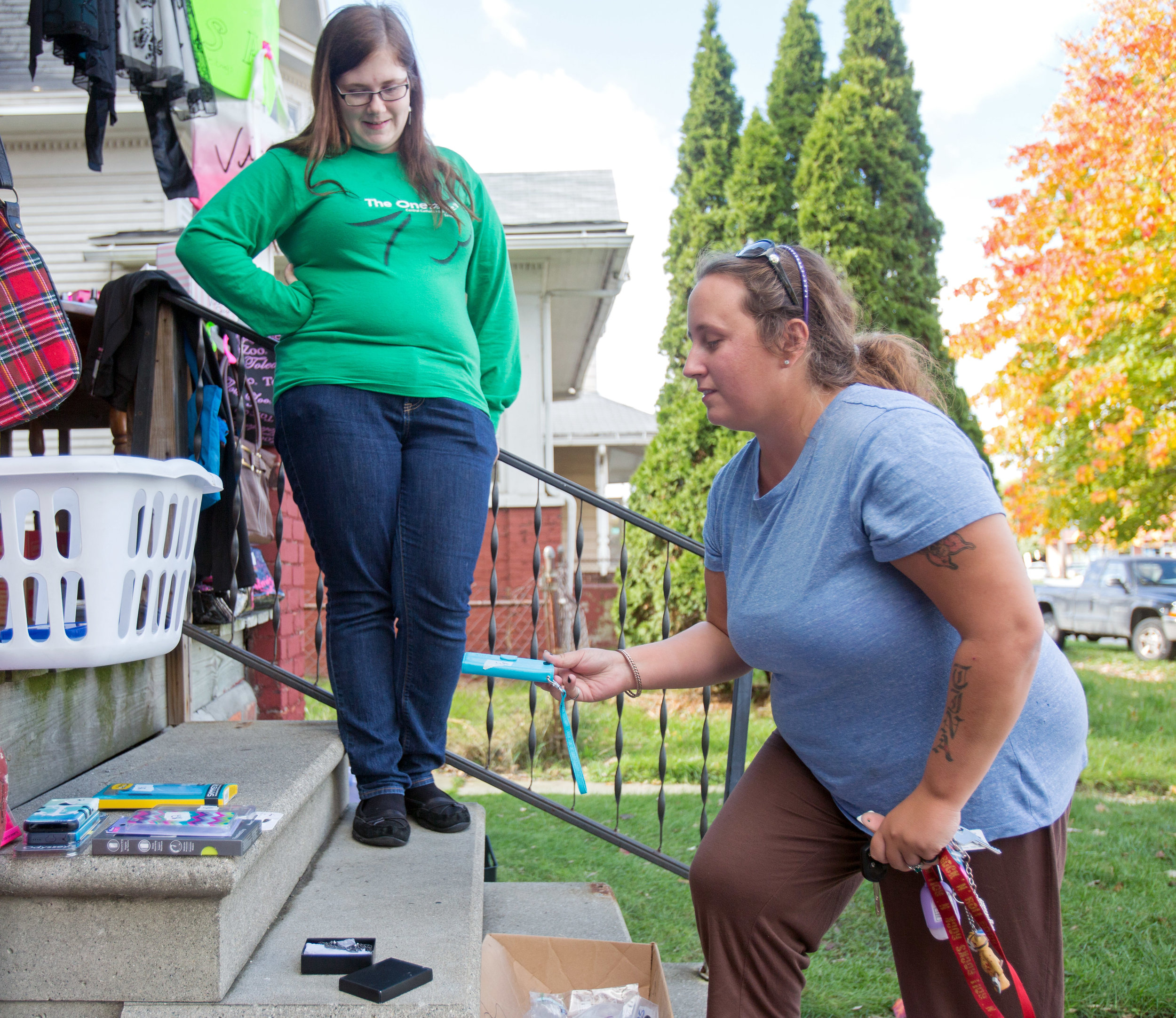 Theresa Szilagye, left, hosts a porch sale on the steps of her home on South Ave. in Toledo as Kristina Benner of Toledo looks through the different phone cases for sale on Thursday, Nov. 3, 2016.