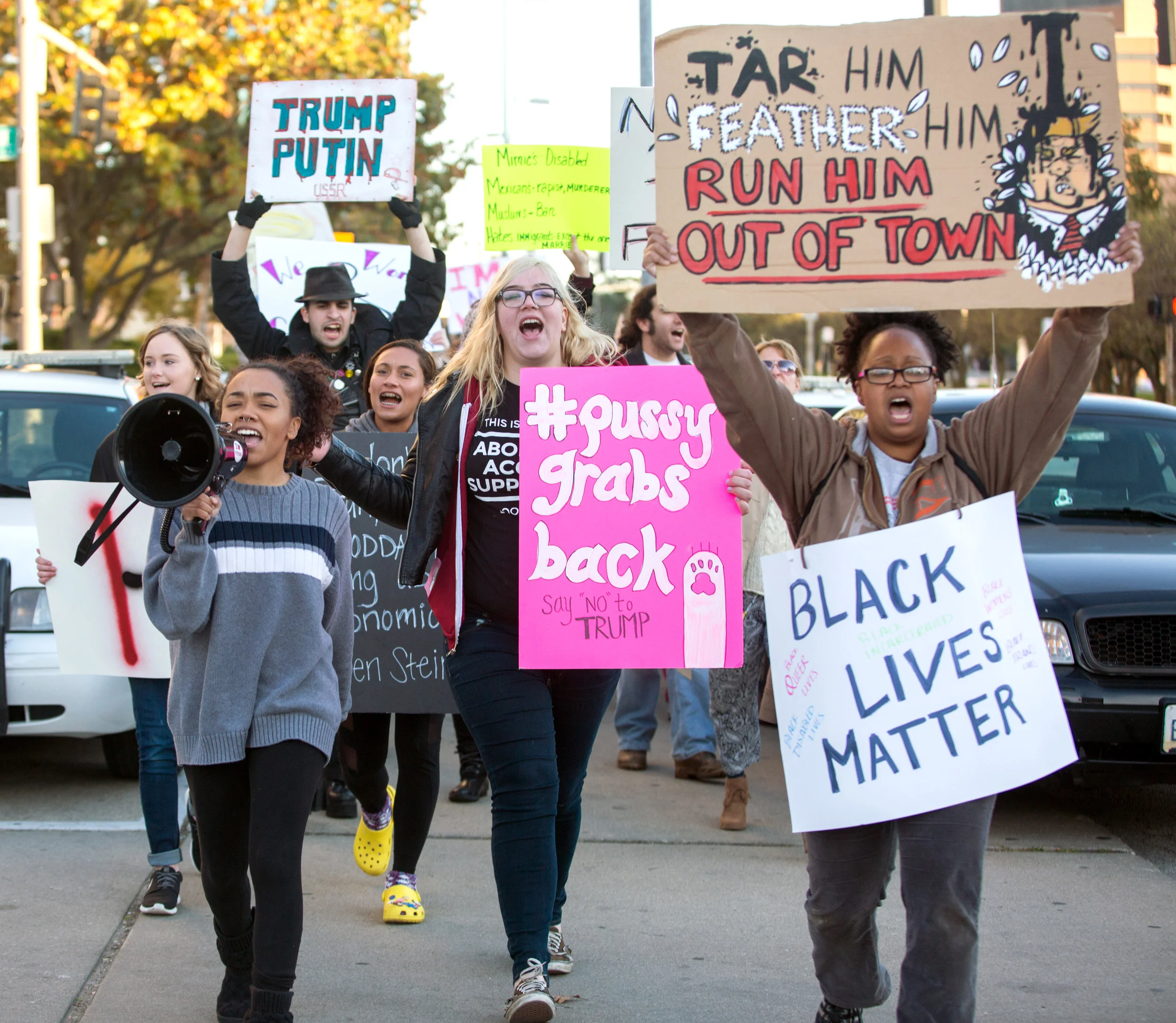 Angel Esparza of Toledo, left, leads the protest march that she organized down Jackson St. past the Toledo Police Department with Allie Lahey, center, and Shannon Frye, right, in downtown Toledo on Saturday, Nov. 12, 2016.