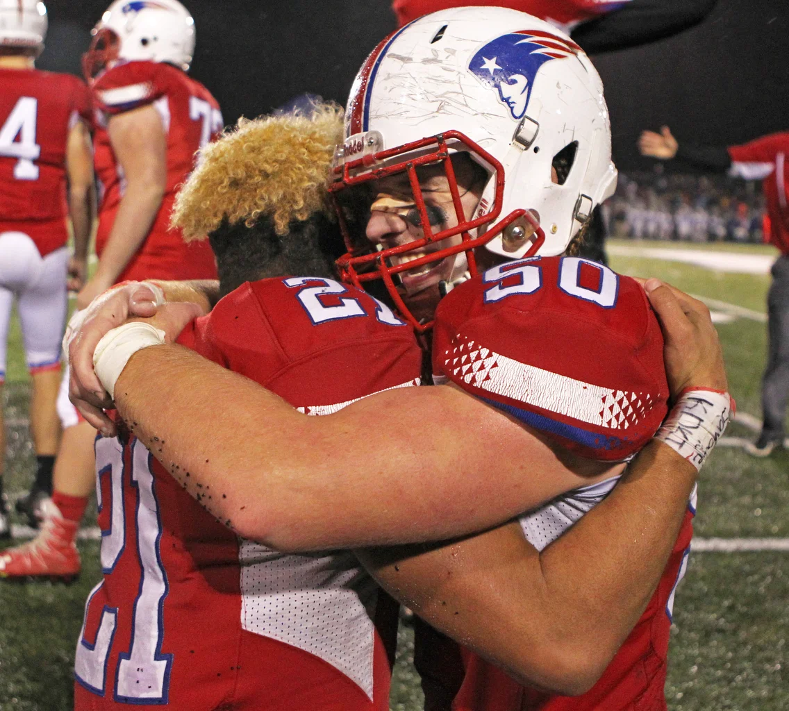  Patrick Henry High School running back Donny Johnson (21) celebrates with tackle Damian Lanzer (50) on the sideline after the team's 21-19 victory over Ayerville High School in the OSHAA Div. VI final football game at Napoleon High School in Napoleo