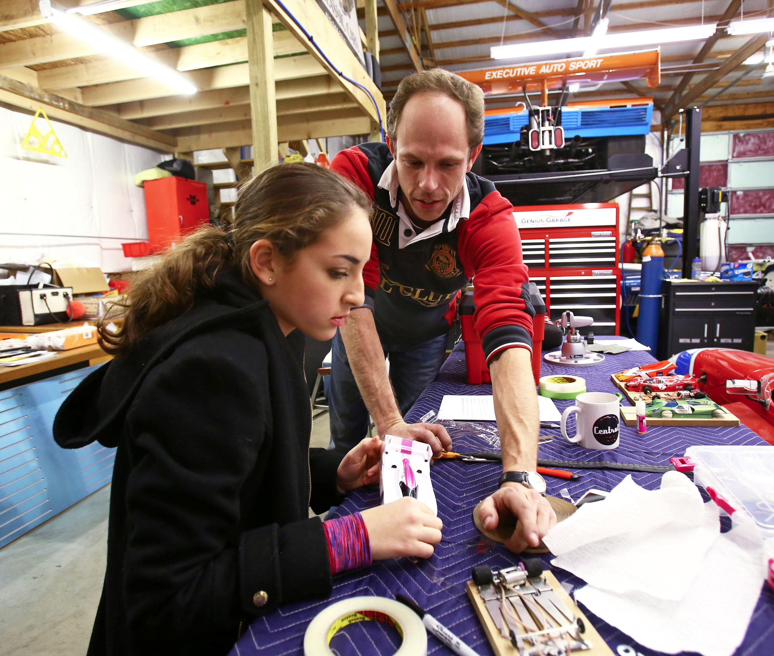 President of Genius Garage Casey Putsch, right, gives Kenna Edwards of Sylvania pointers on how give her slot car some extra stability on the track at the Genius Garage Racing Team's garage located in the Sylvania Business Plaza on W. Central Avenue in Sylvania, Oh. on Monday, Dec. 12, 2016.