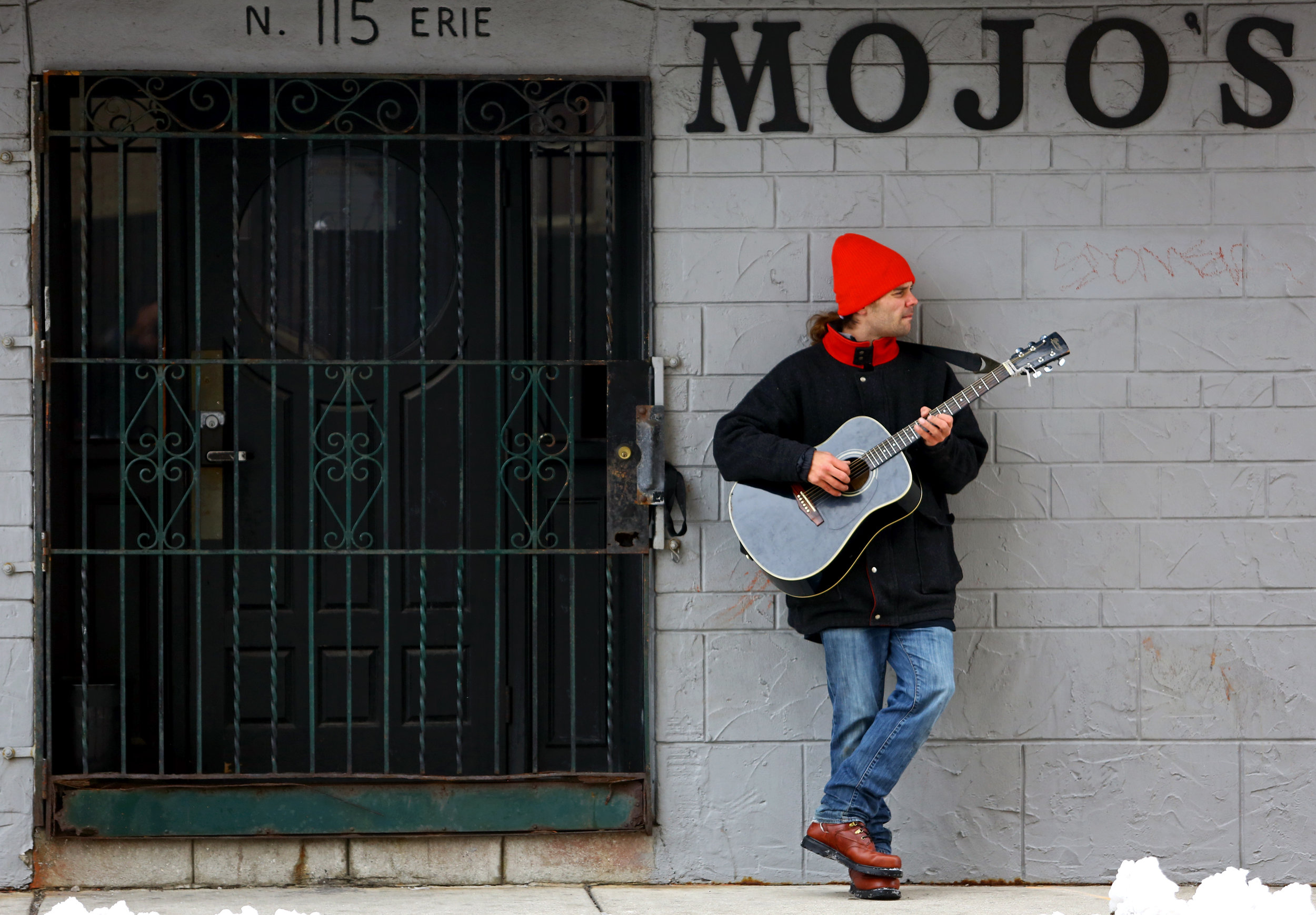 Andrew Schively of Toledo plays his guitar outside of Mojo's on Erie Street in downtown Toledo, Oh. on Tuesday, Dec. 13, 2016. Schively normally does what he calls a "walk and jam" because he likes to play his guitar outside of his apartment, but today he stopped at Mojo's to visit a friend who works at the bar.