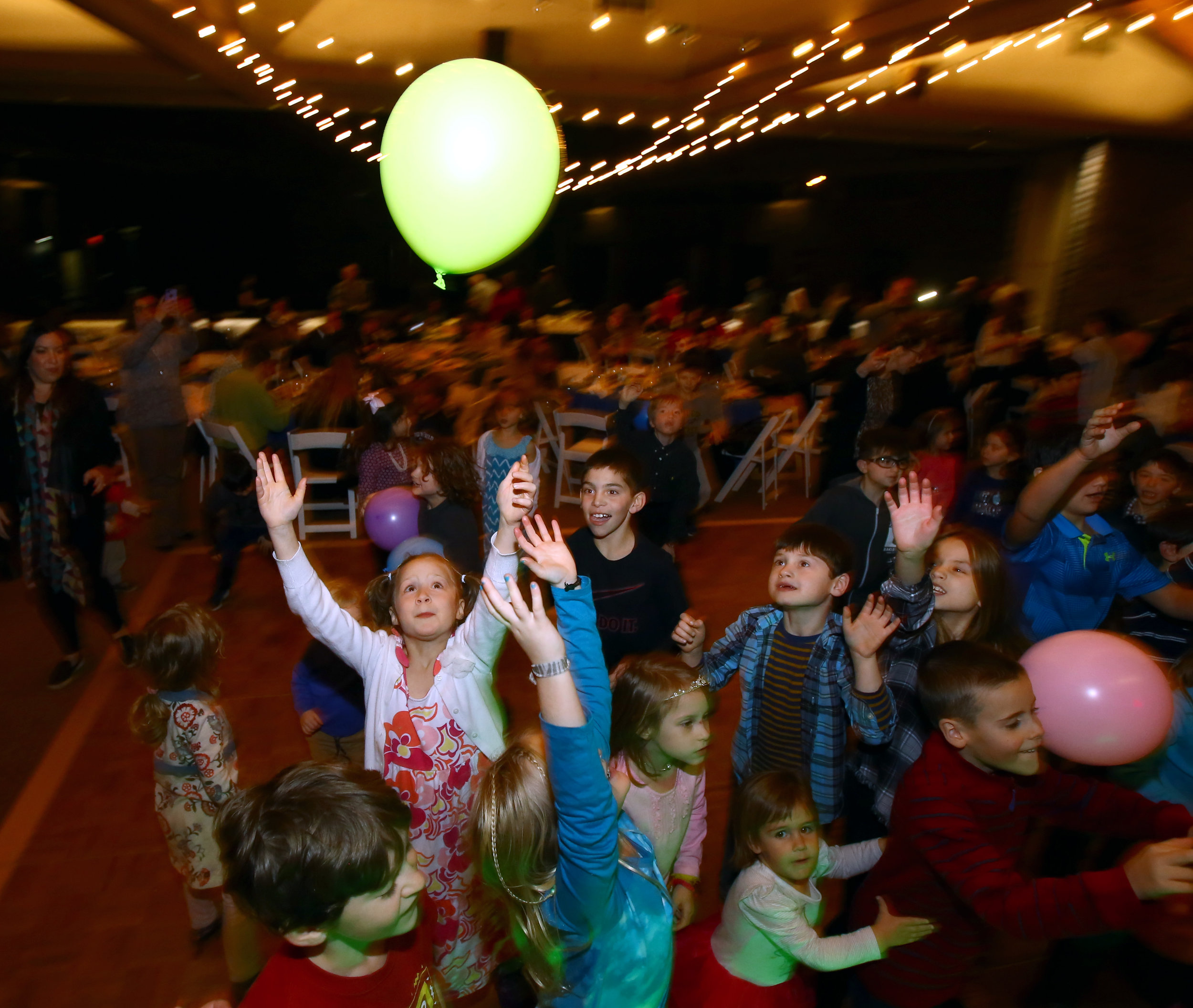 Rebeca Weingarten, 7, of Sylvania reaches for a balloon on the dance floor during the Temple Shomer Emunim's Hanukkah celebration at the temple in Sylvania, Oh. on Sunday, Dec. 18, 2016. 