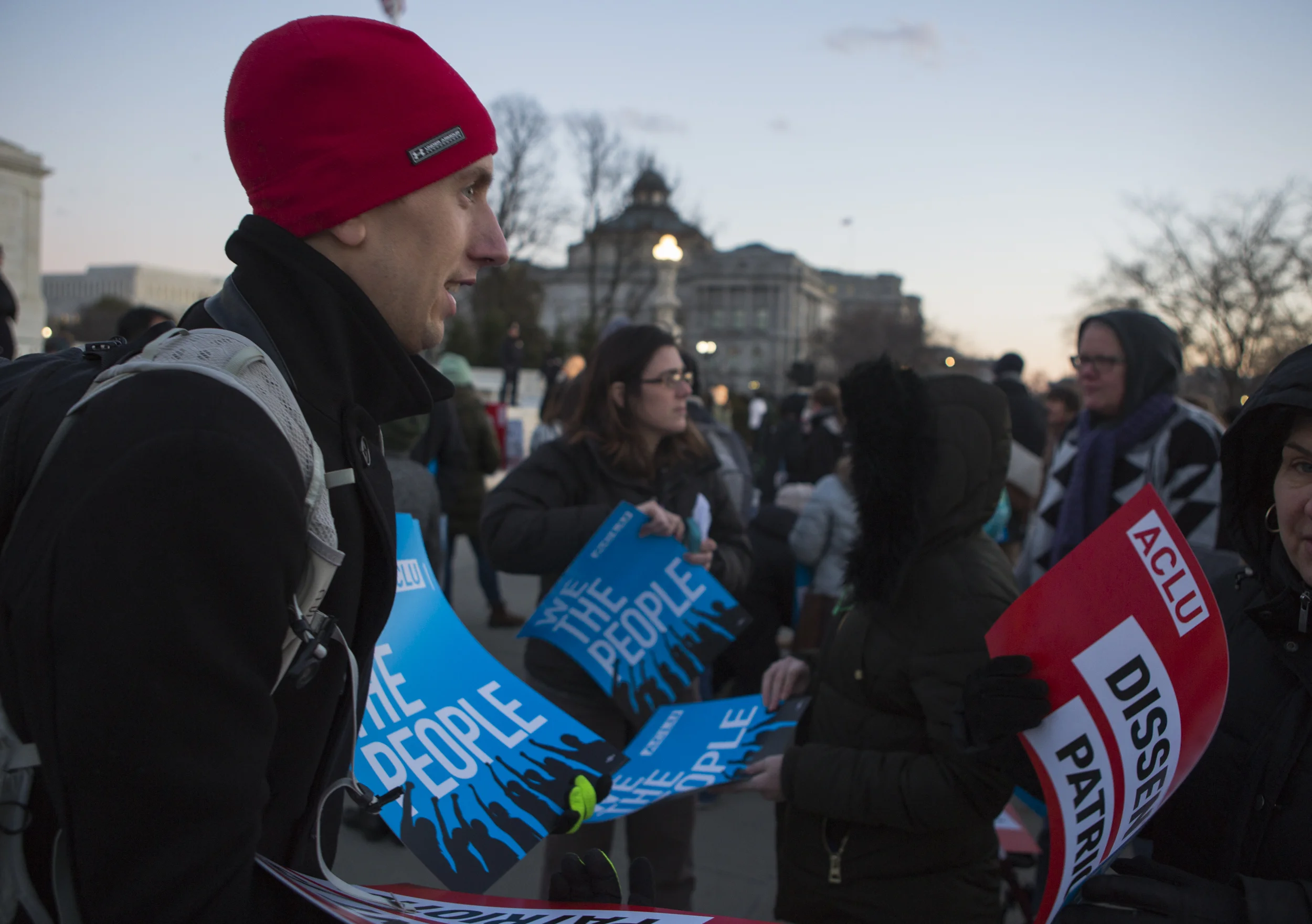 A UCLA volunteer hands out protest signs to rally participants gathering at the Supreme Court Steps.